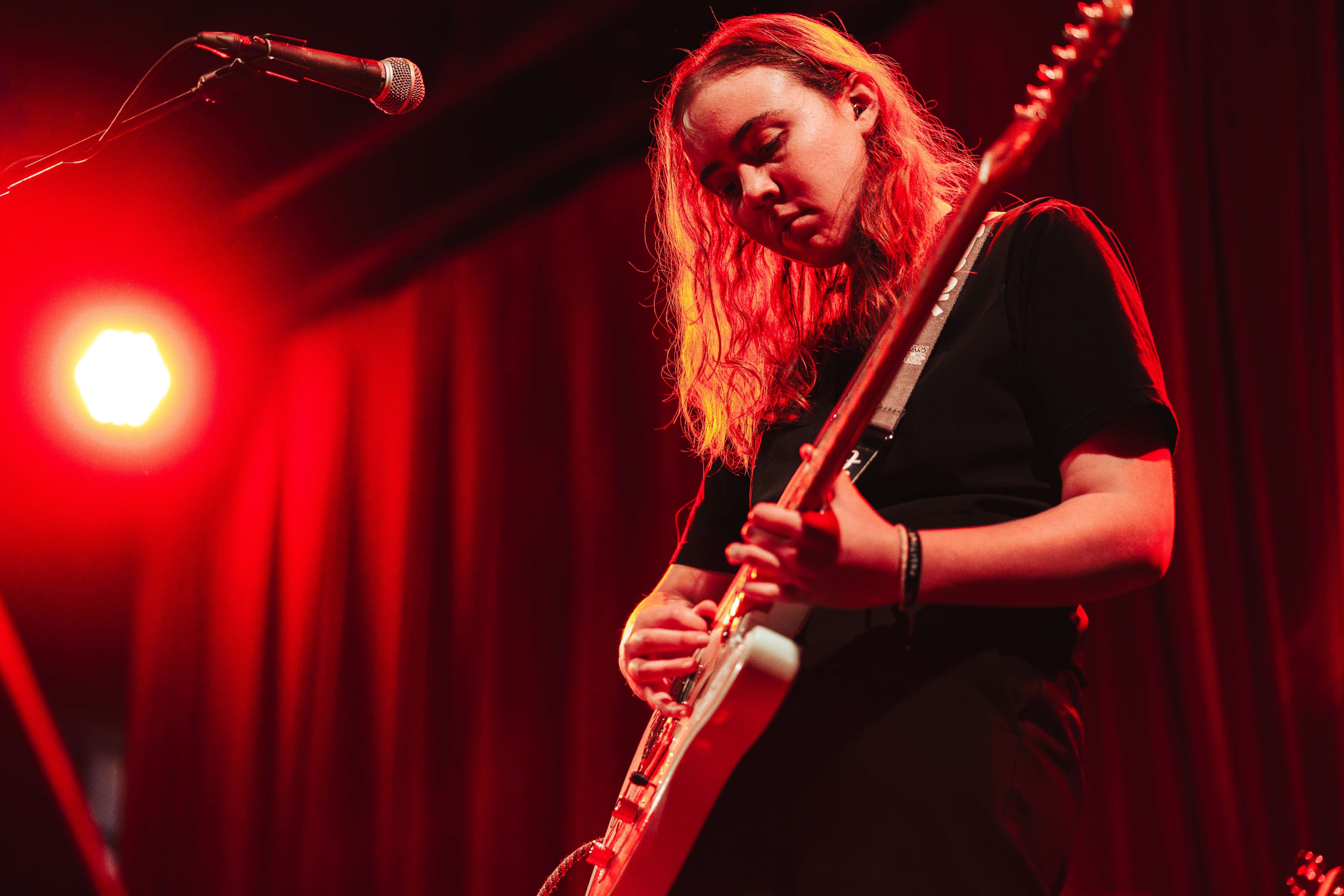 a woman playing a guitar in front of a microphone
