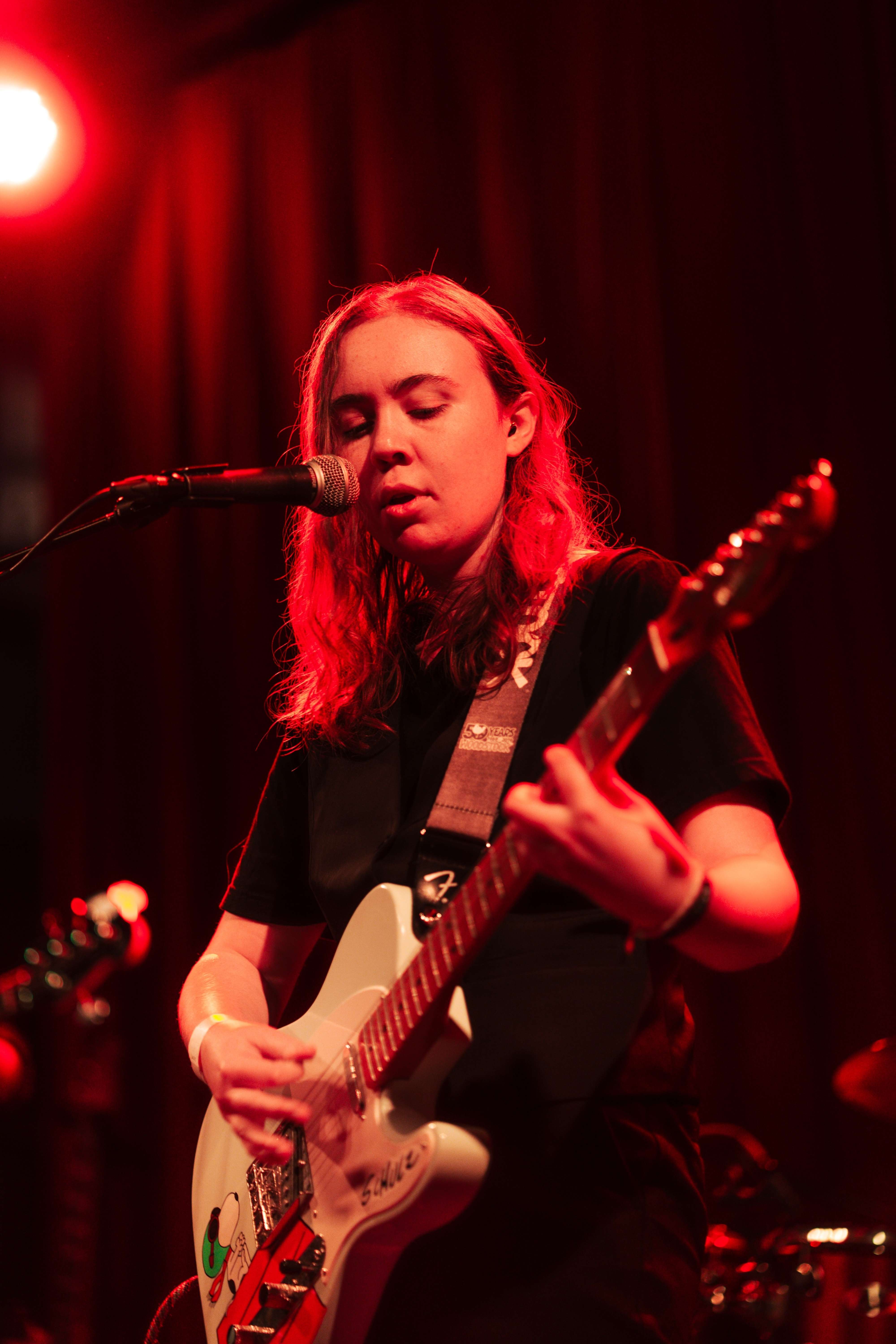 a woman playing a guitar in front of a microphone