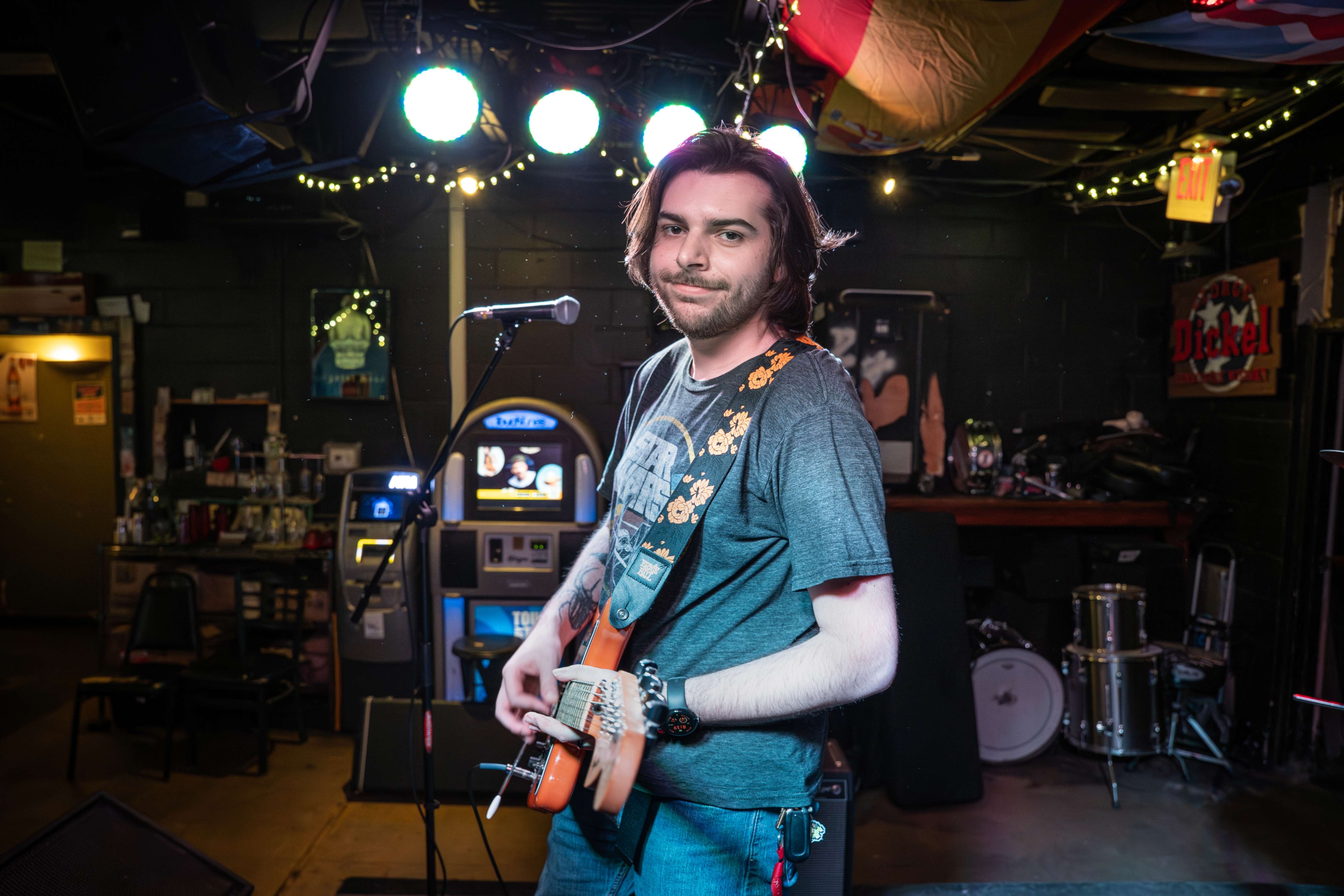 a man standing in front of a microphone in a bar