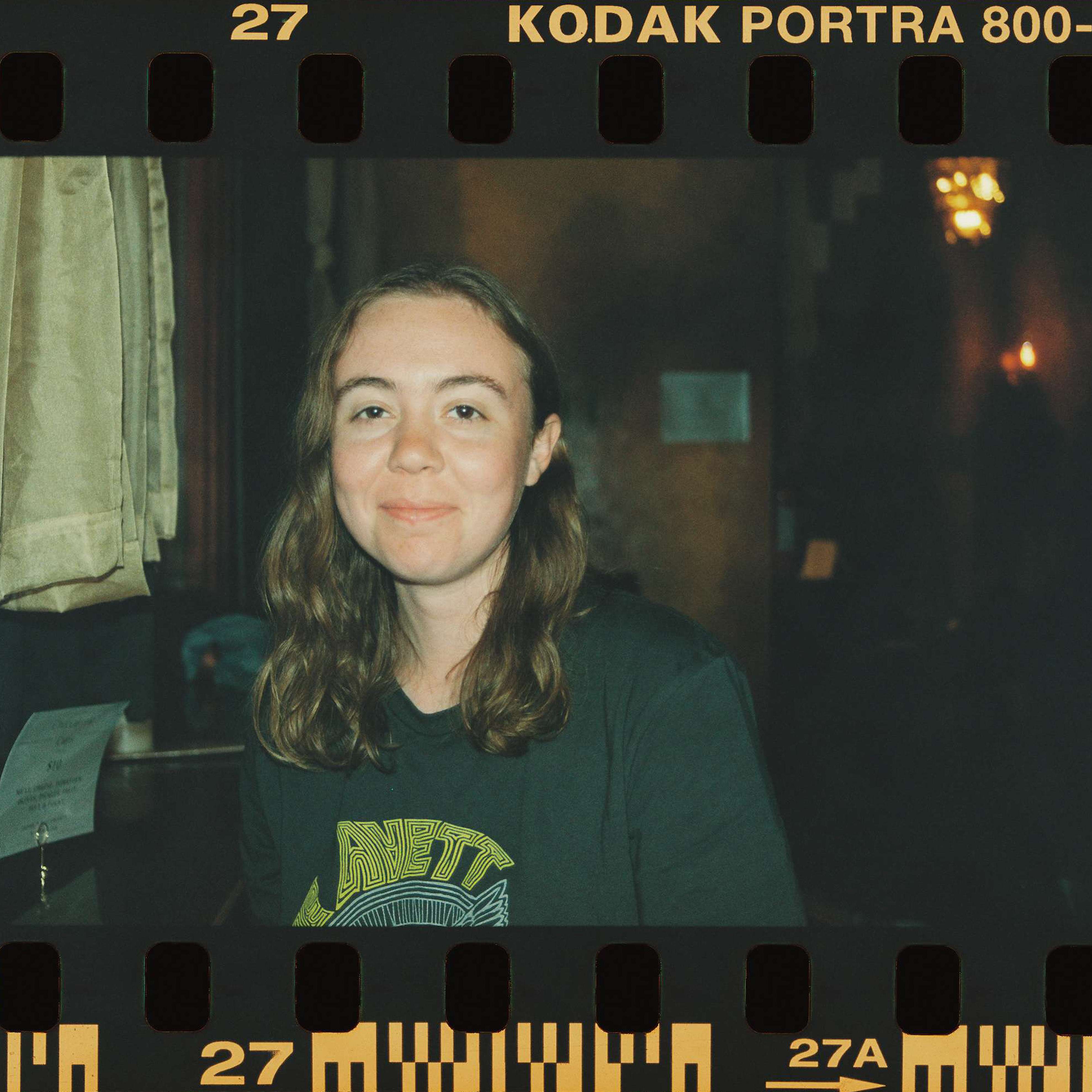 a woman in a black shirt is smiling in front of a kodachrome frame