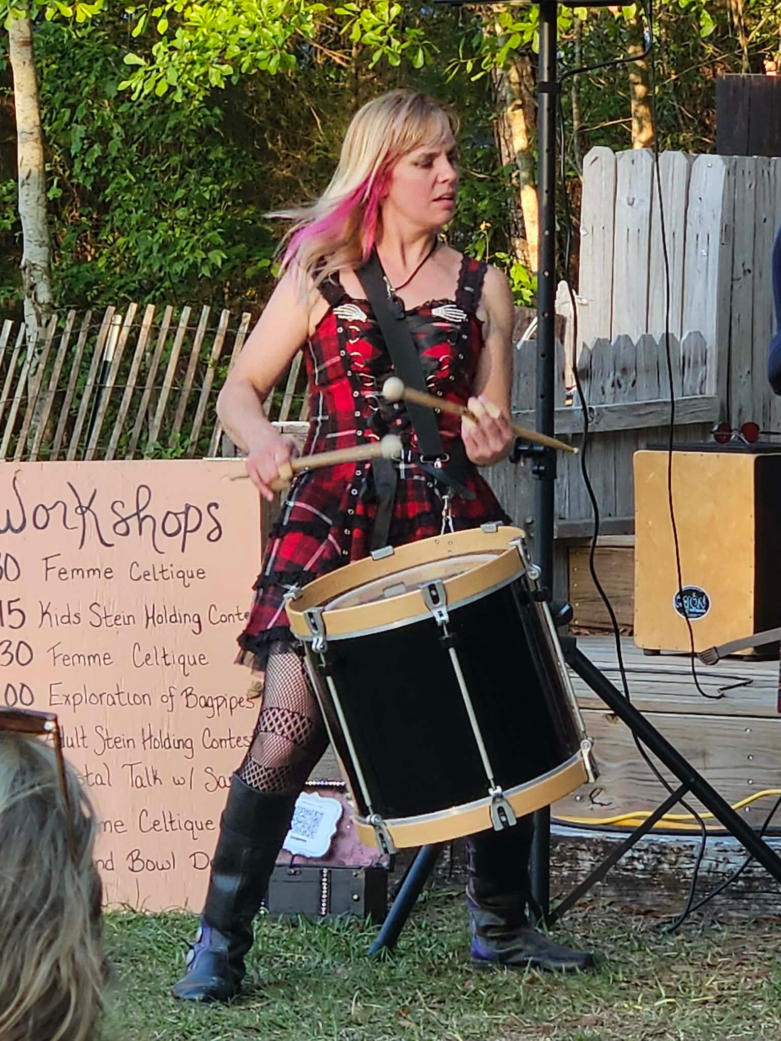 a woman playing a drum in front of a sign