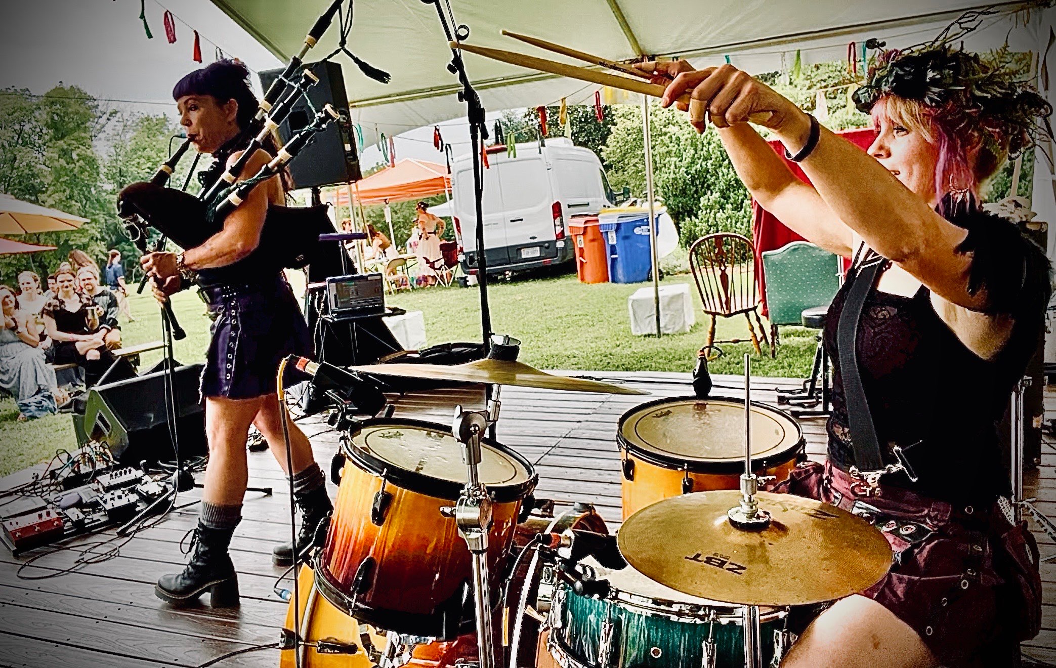 two women playing drums on a wooden deck