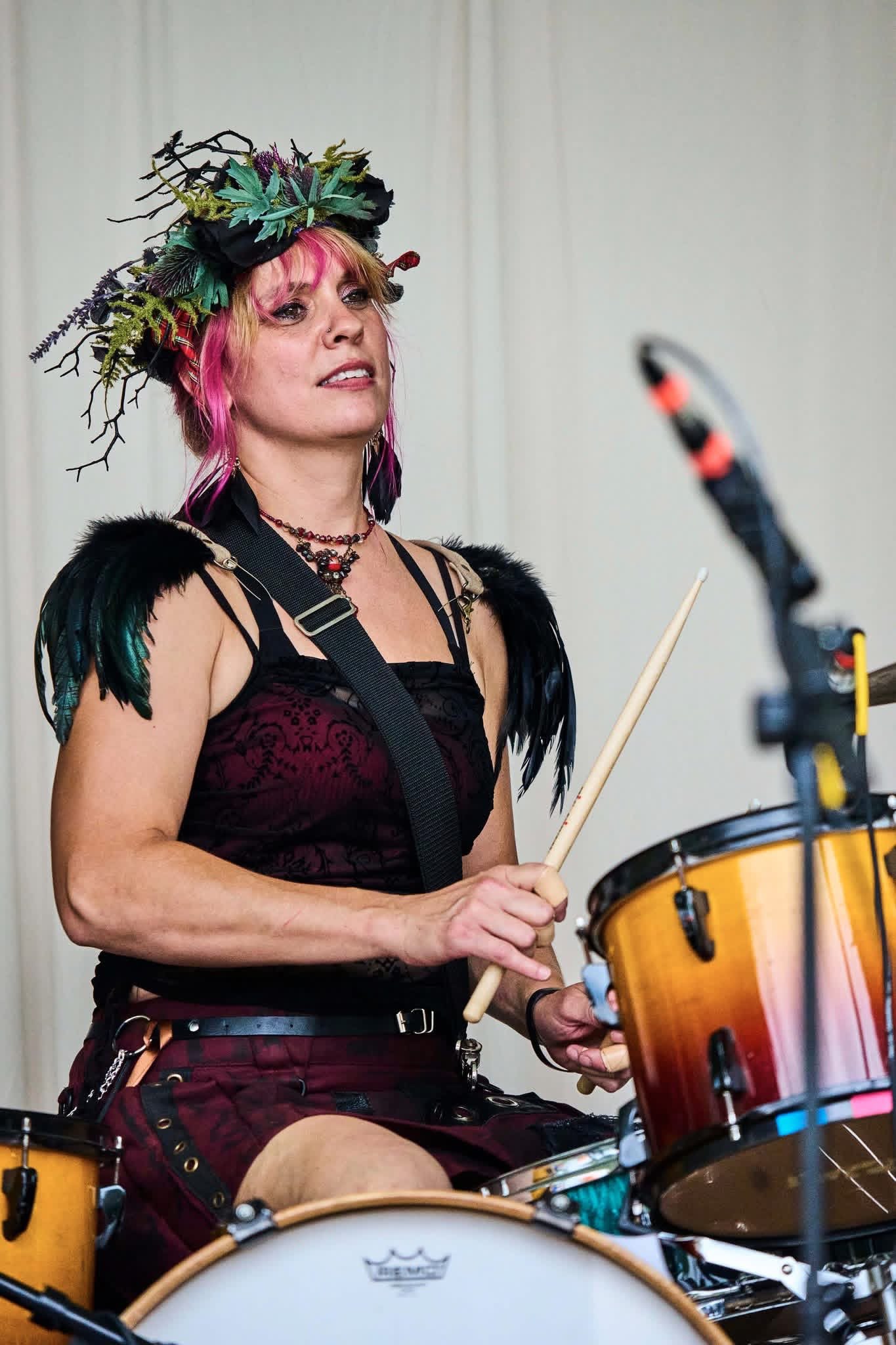 a woman playing drums with a flower crown on her head