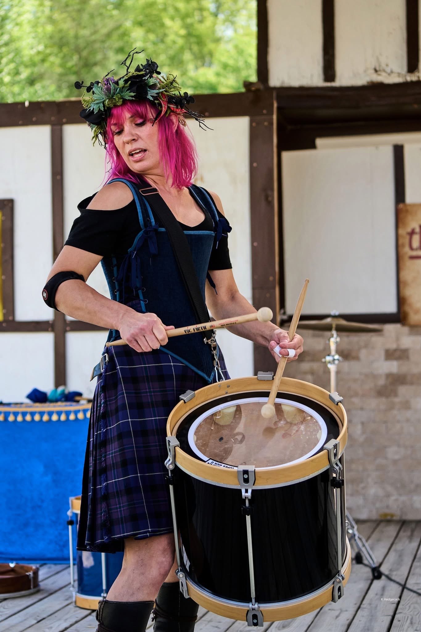 a woman in a kilt playing a drum