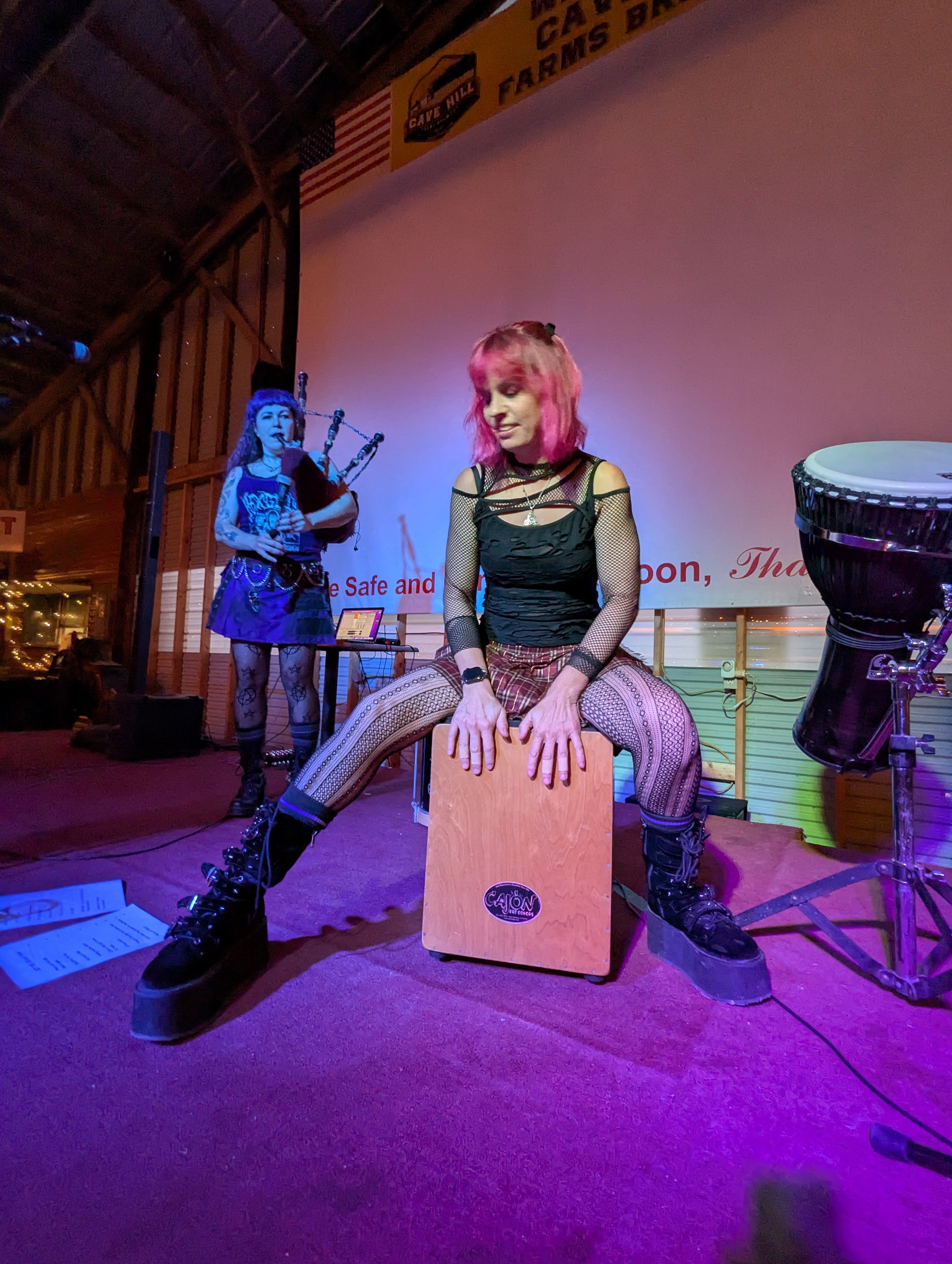 a woman is sitting on a stage with a drum in front of her