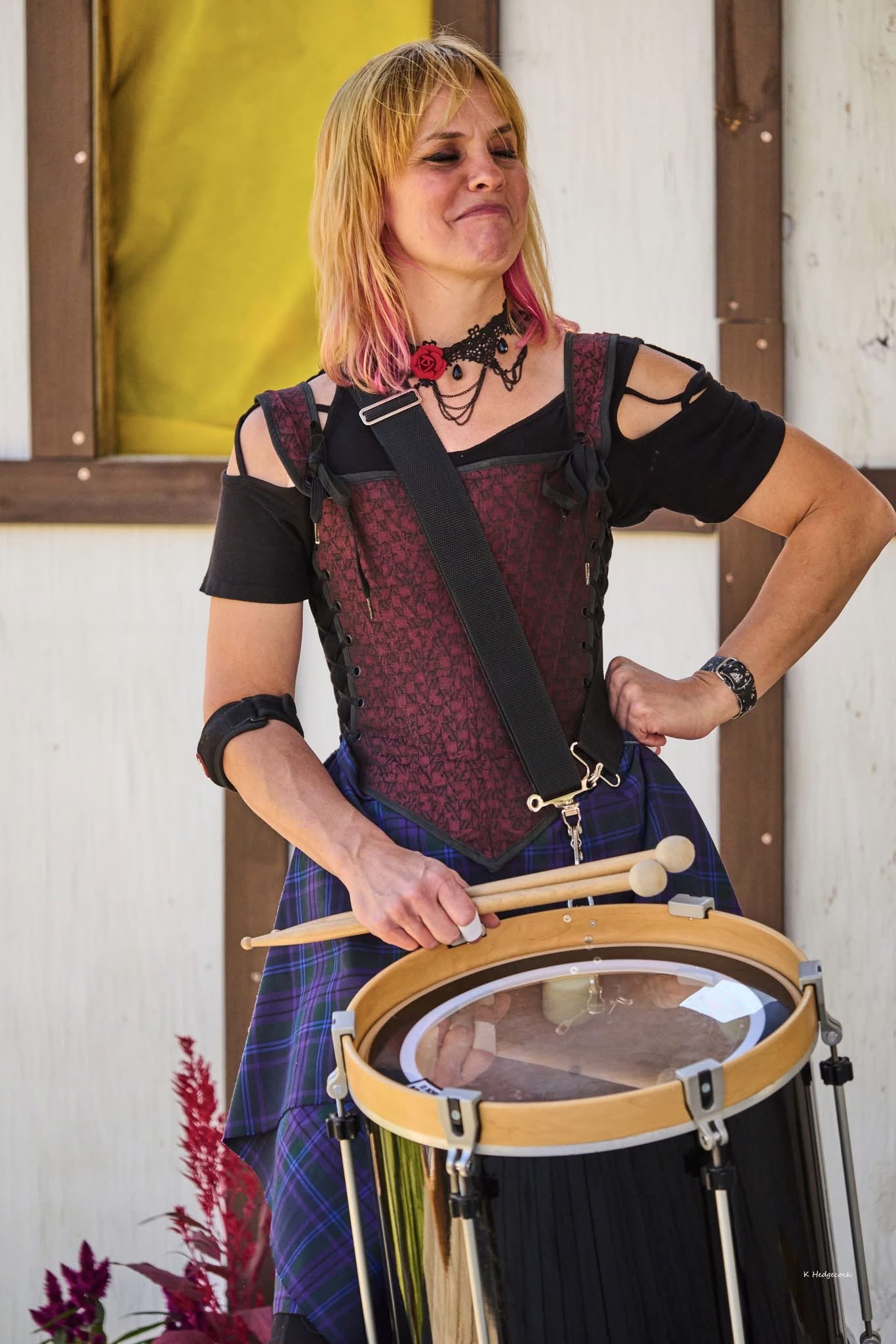 a woman in a kilt is holding a drum