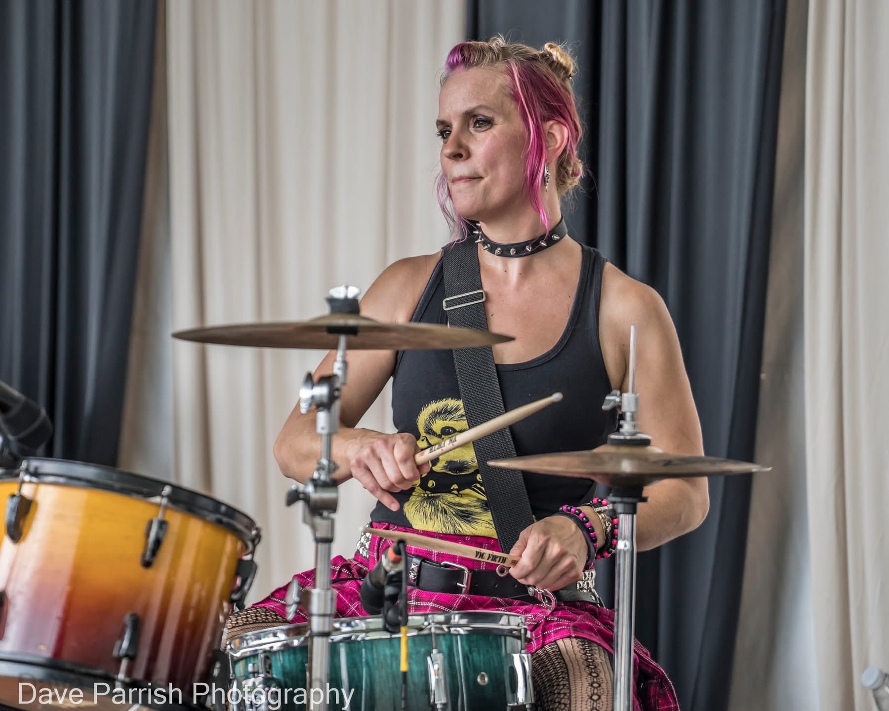a woman with pink hair playing drums