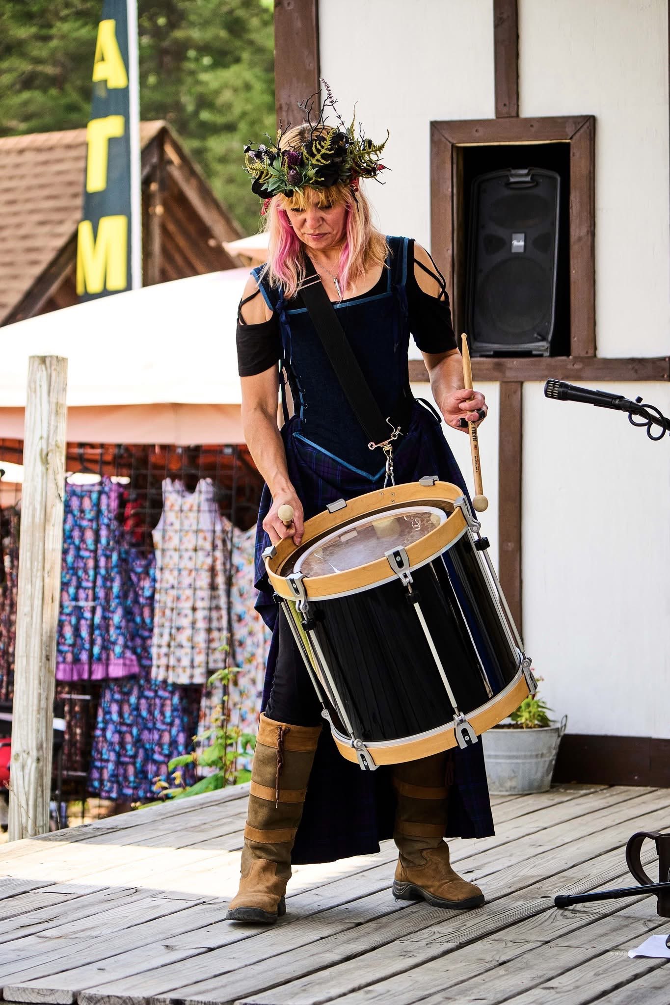 a woman playing a drum on a wooden deck
