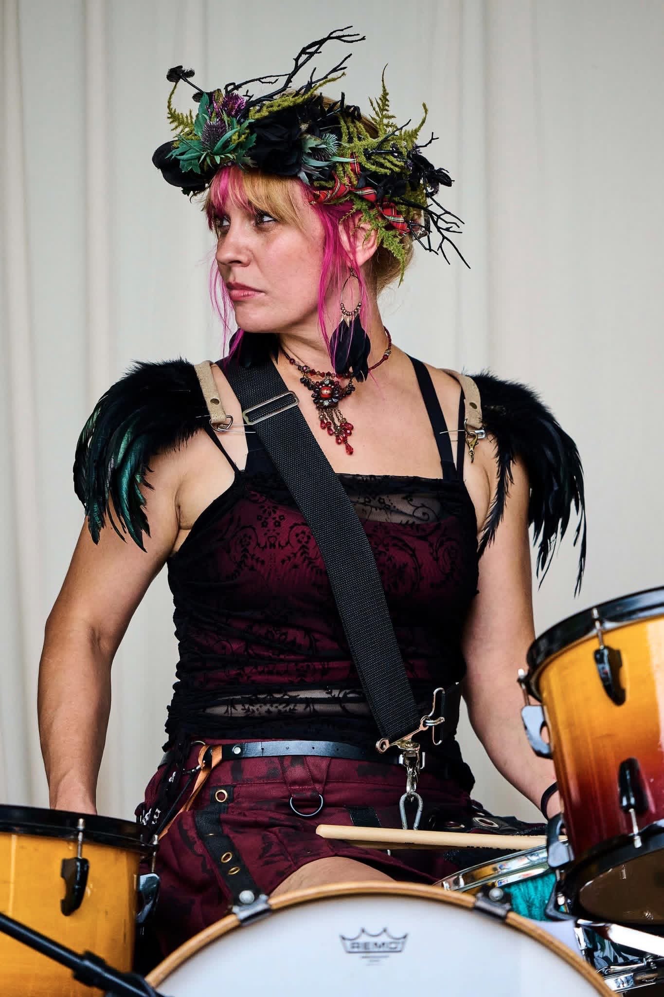 a woman wearing a hat and playing drums