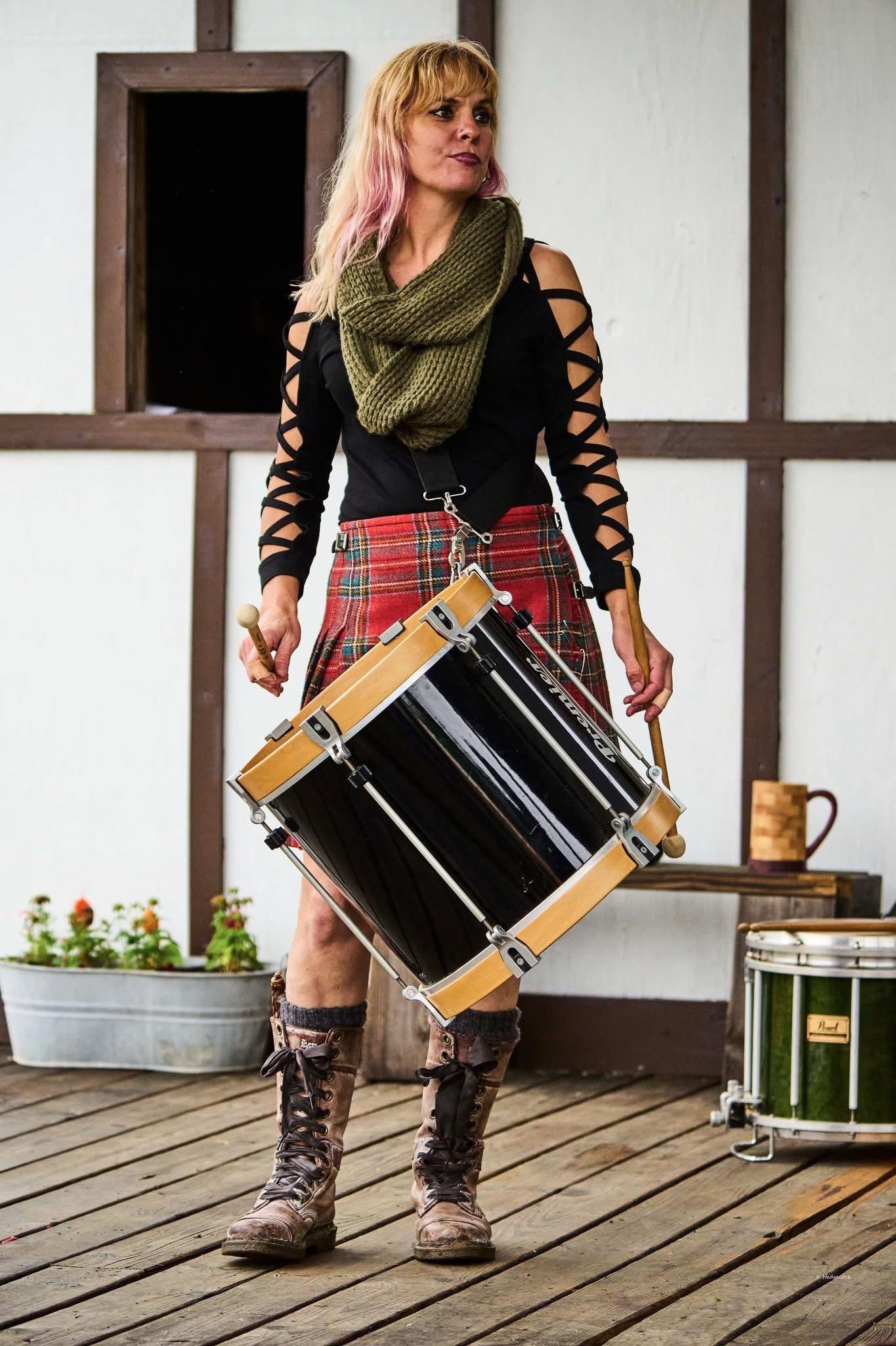 a woman in a kilt holding a drum