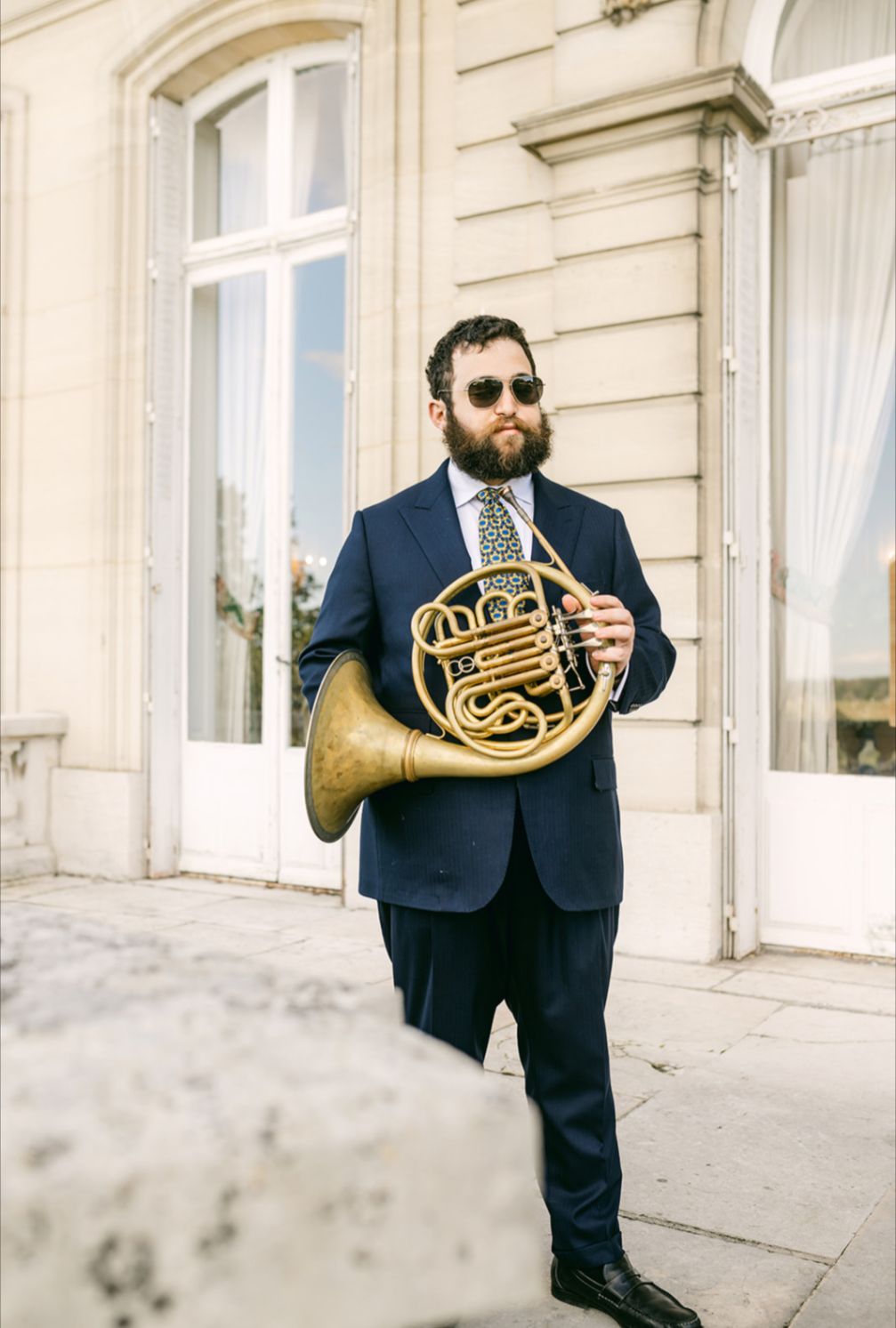 a man in a suit holding a french horn