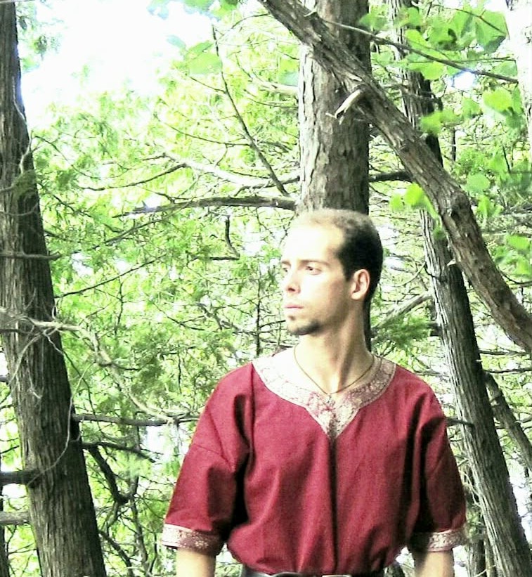 a man in a red shirt standing in the woods