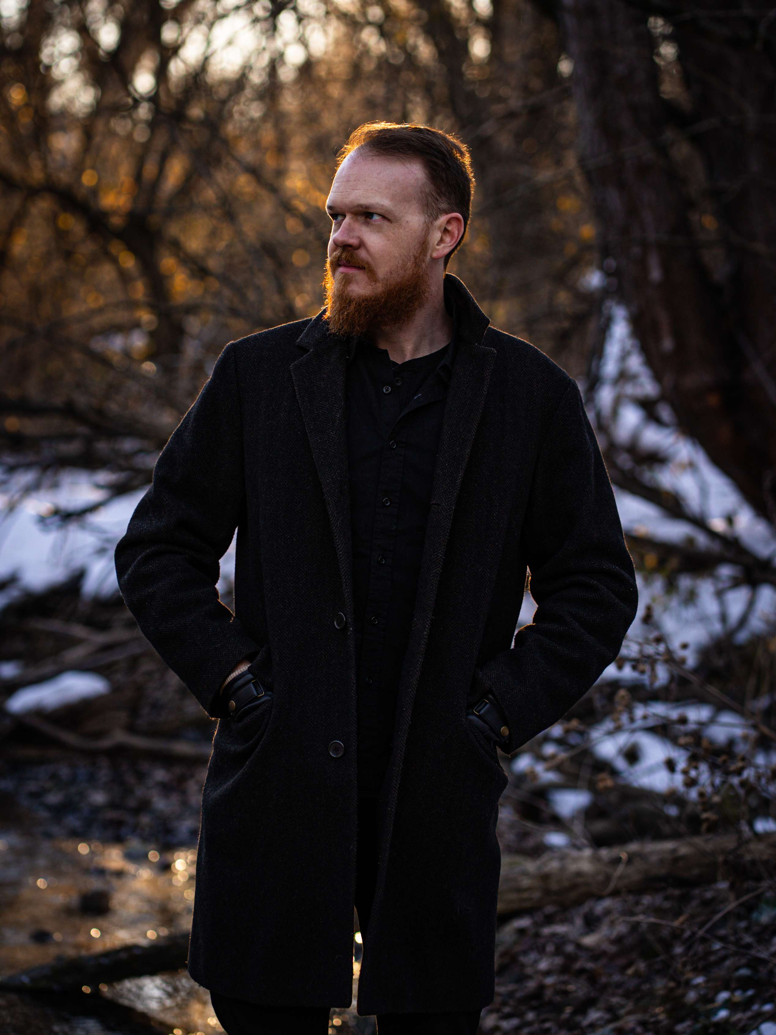a man with a beard standing by a river