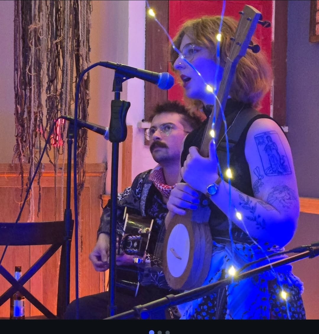 a woman singing and playing a banjo in front of a microphone