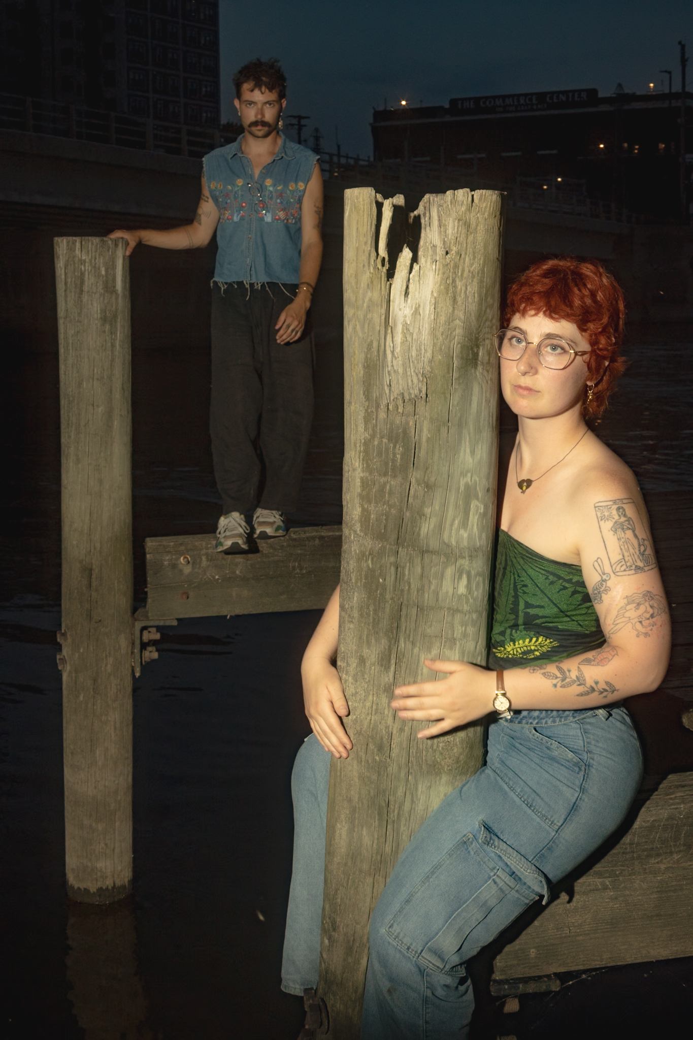 a man and woman posing on wooden poles in the water