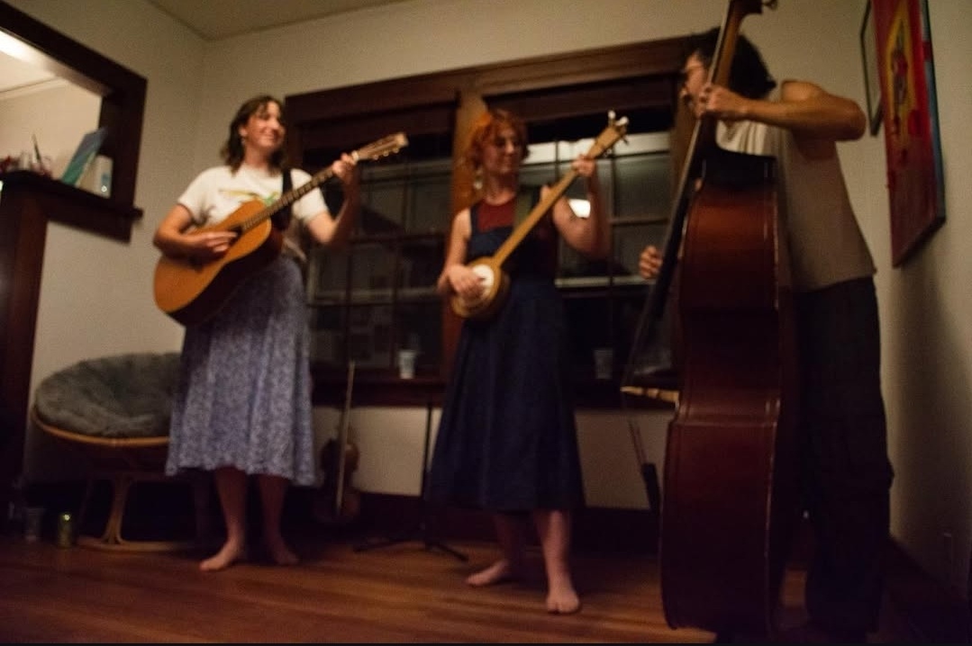 three women playing guitars in a living room