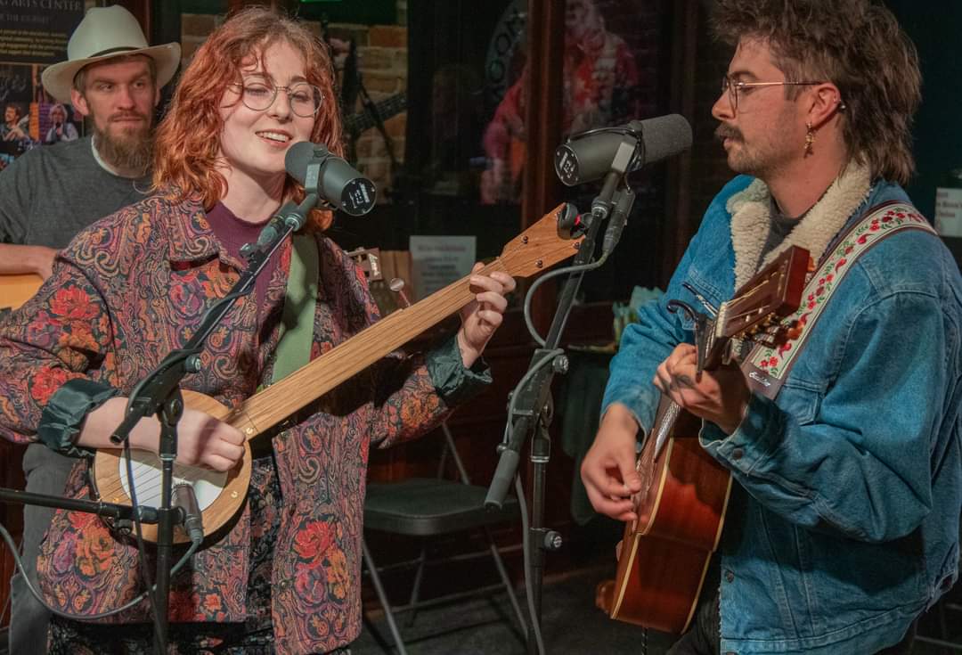 a group of people singing and playing guitars in a recording studio