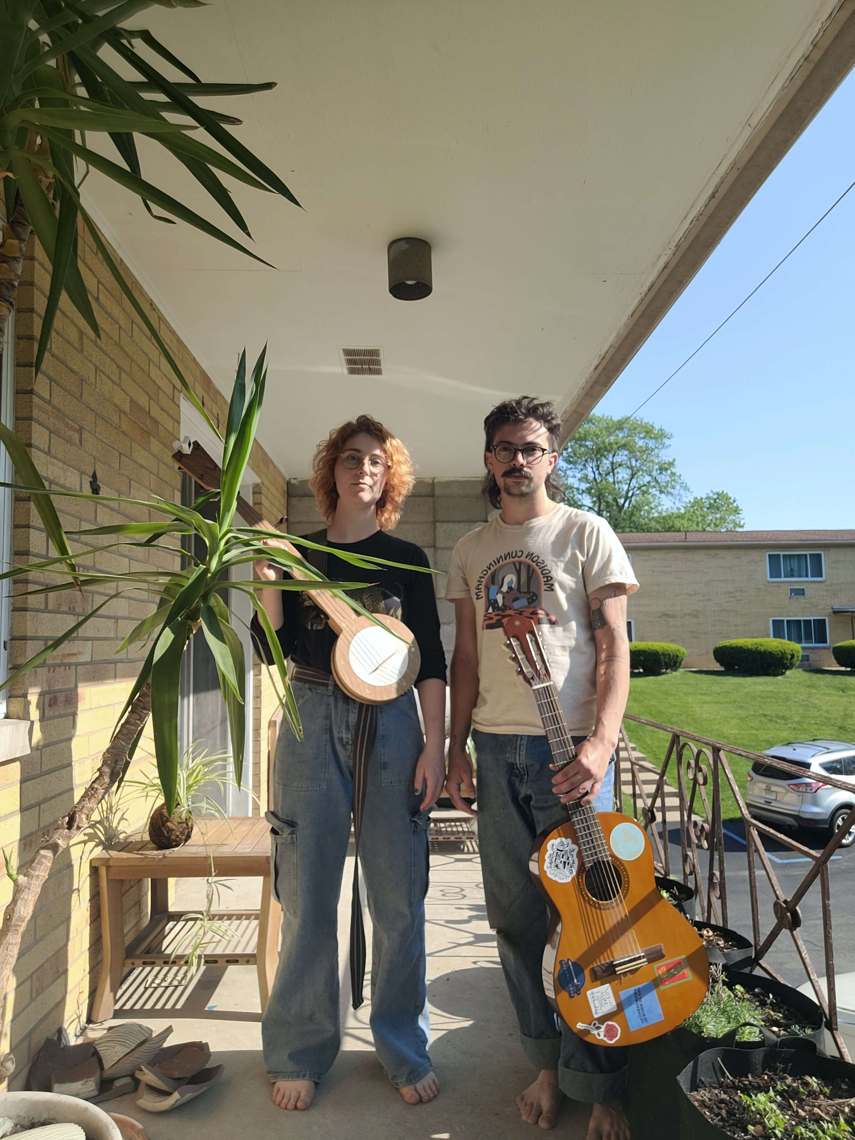 two people standing on a porch with a guitar