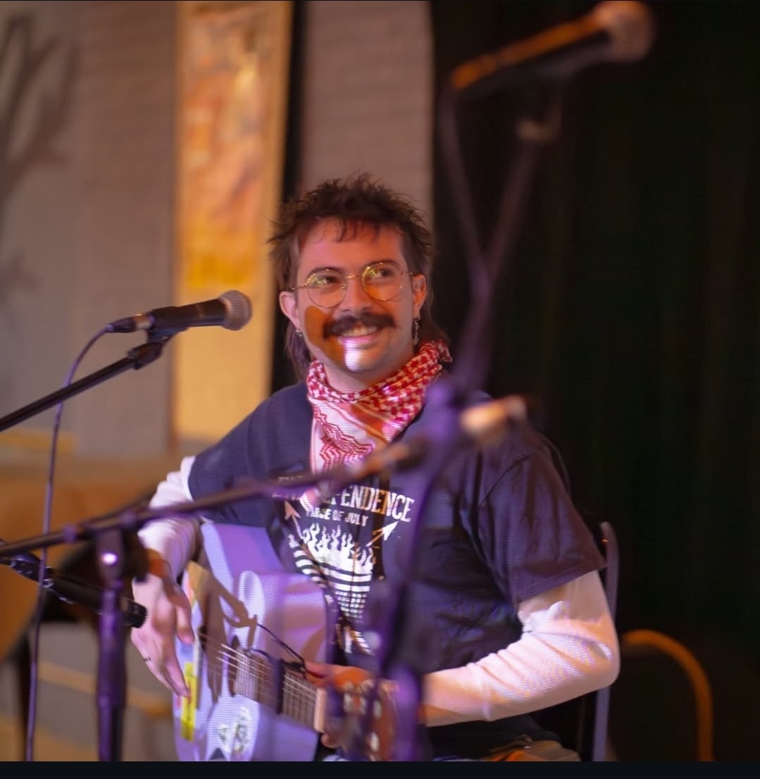 a man playing an acoustic guitar in front of a microphone
