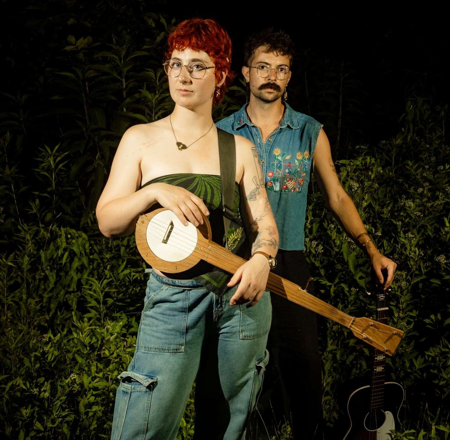 a man and a woman standing next to a banjo in the woods