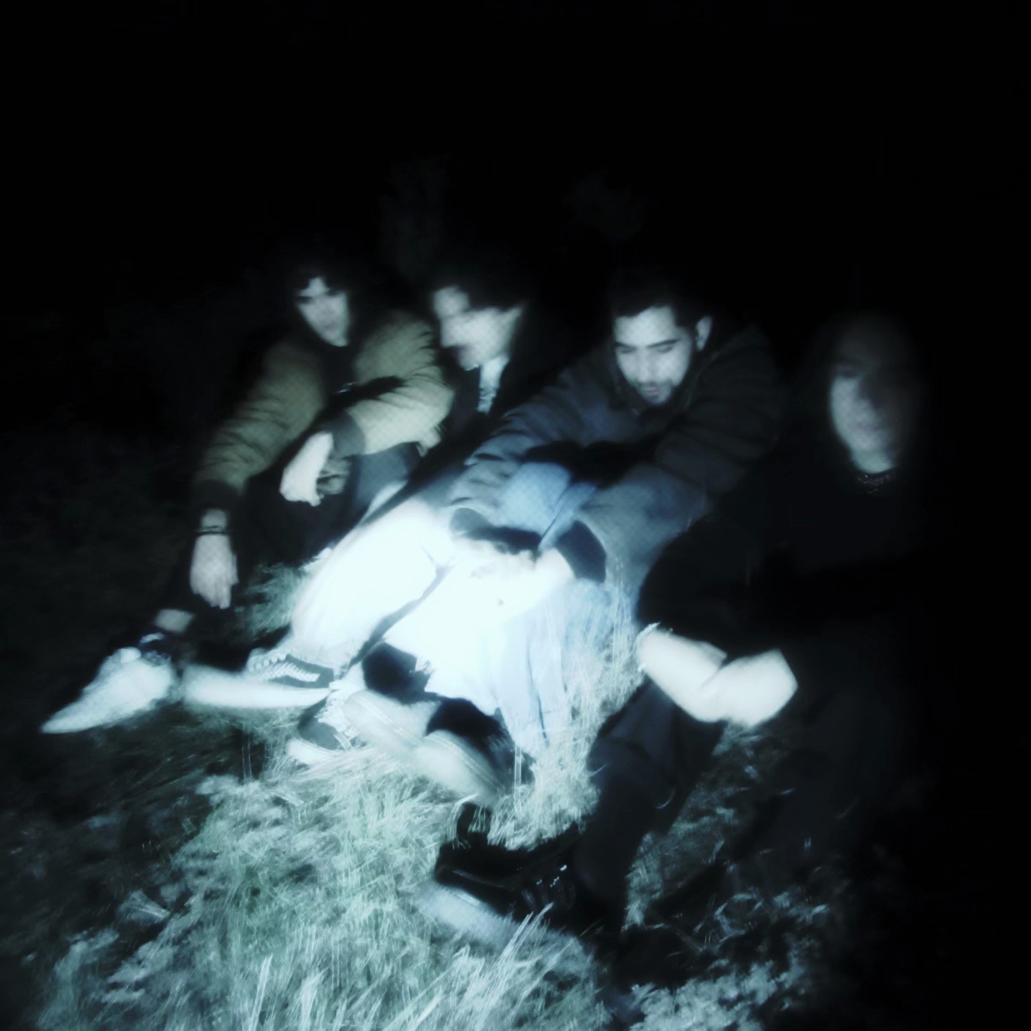 a group of people sitting in the grass at night