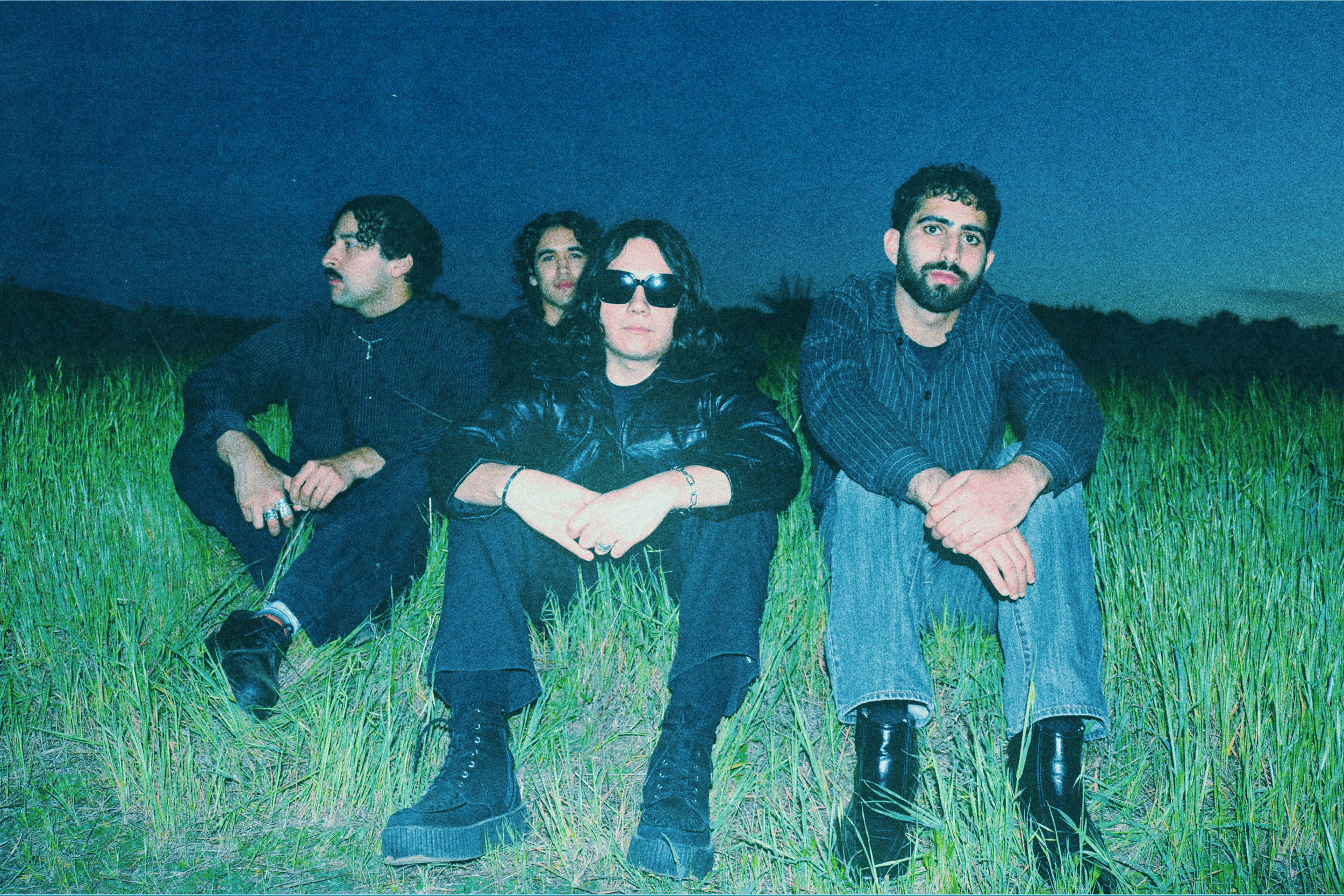 a group of men sitting in a field at night