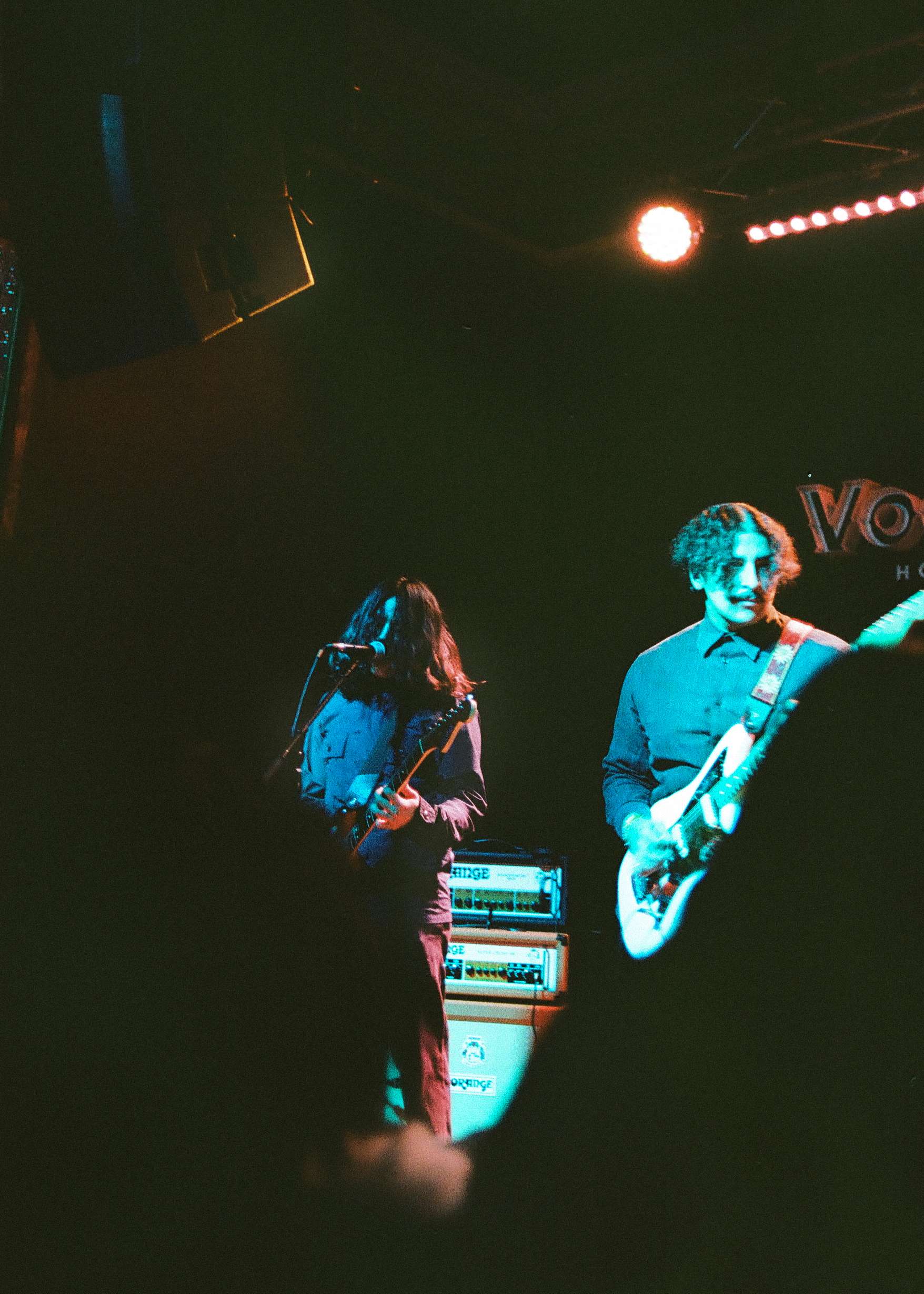 a group of people playing guitar on stage in a dark room