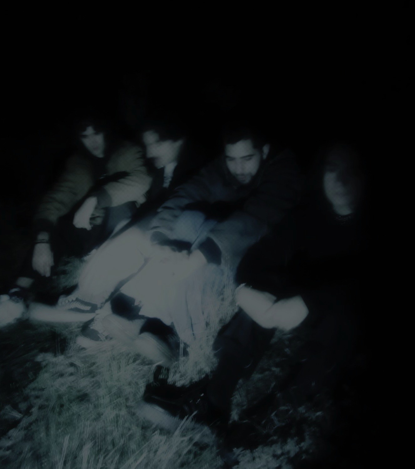 a group of people sitting in the grass at night
