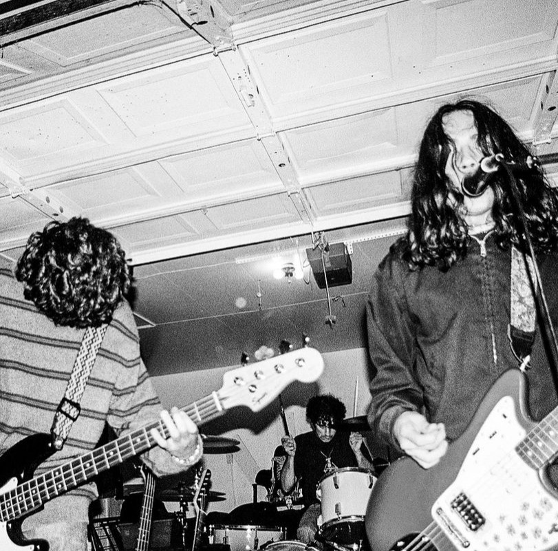 a black and white photo of a group of people playing bass in a garage