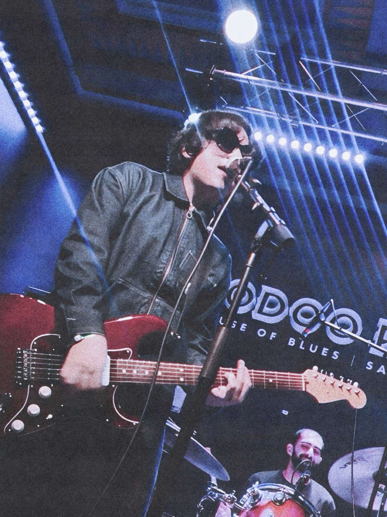 a man is playing a guitar in front of a microphone
