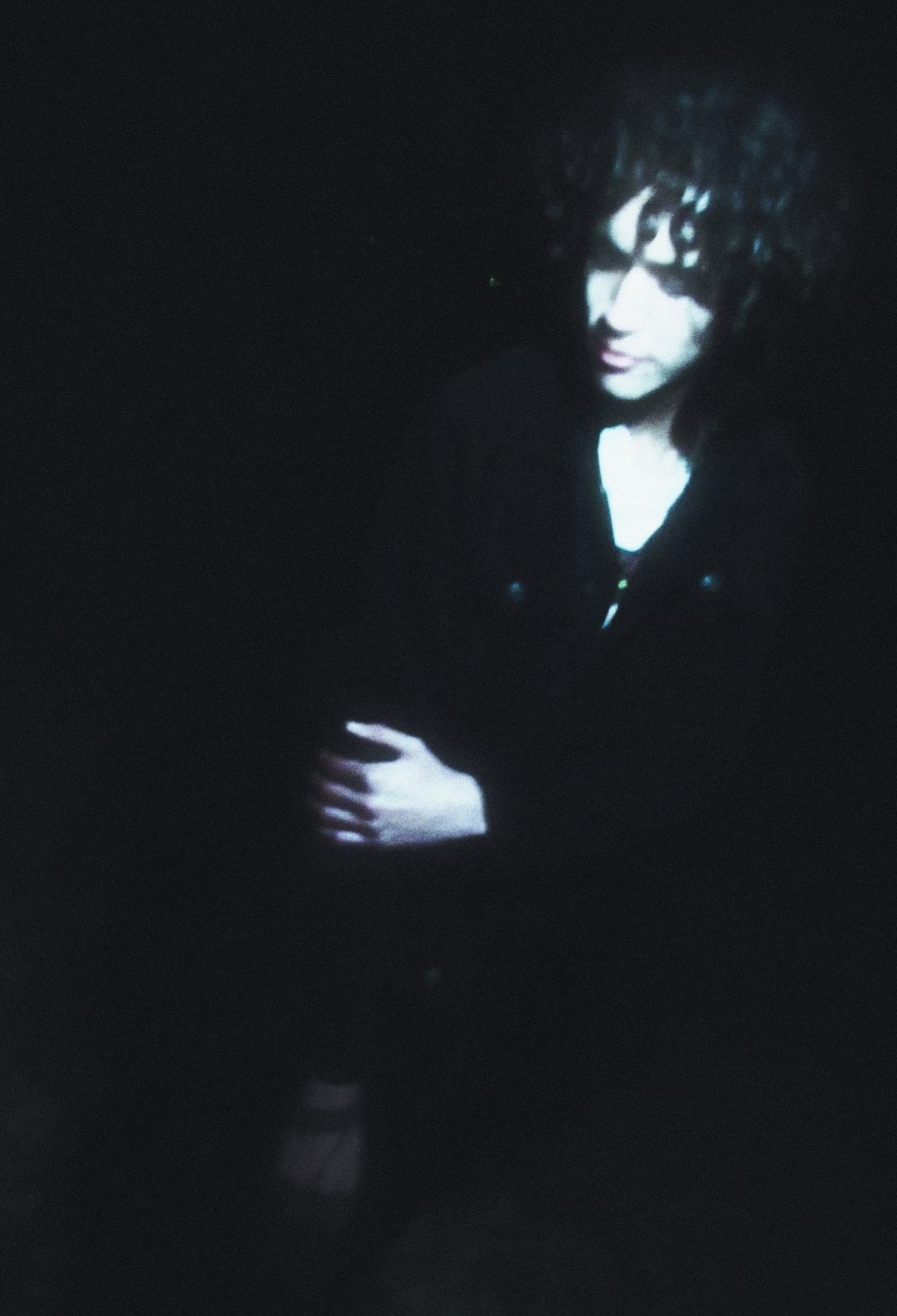 a woman with curly hair sitting in the dark