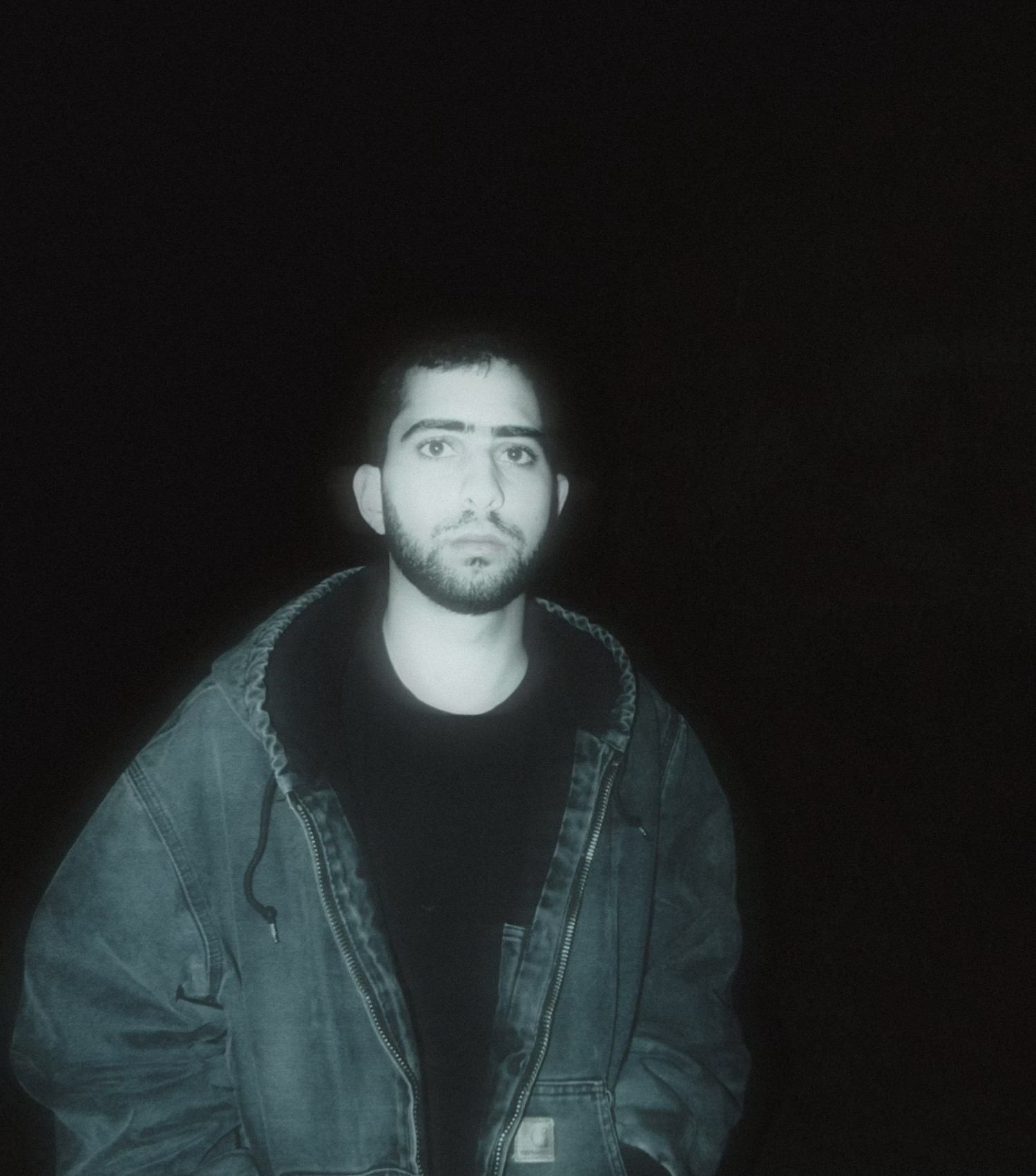 a man in a jacket standing in the dark