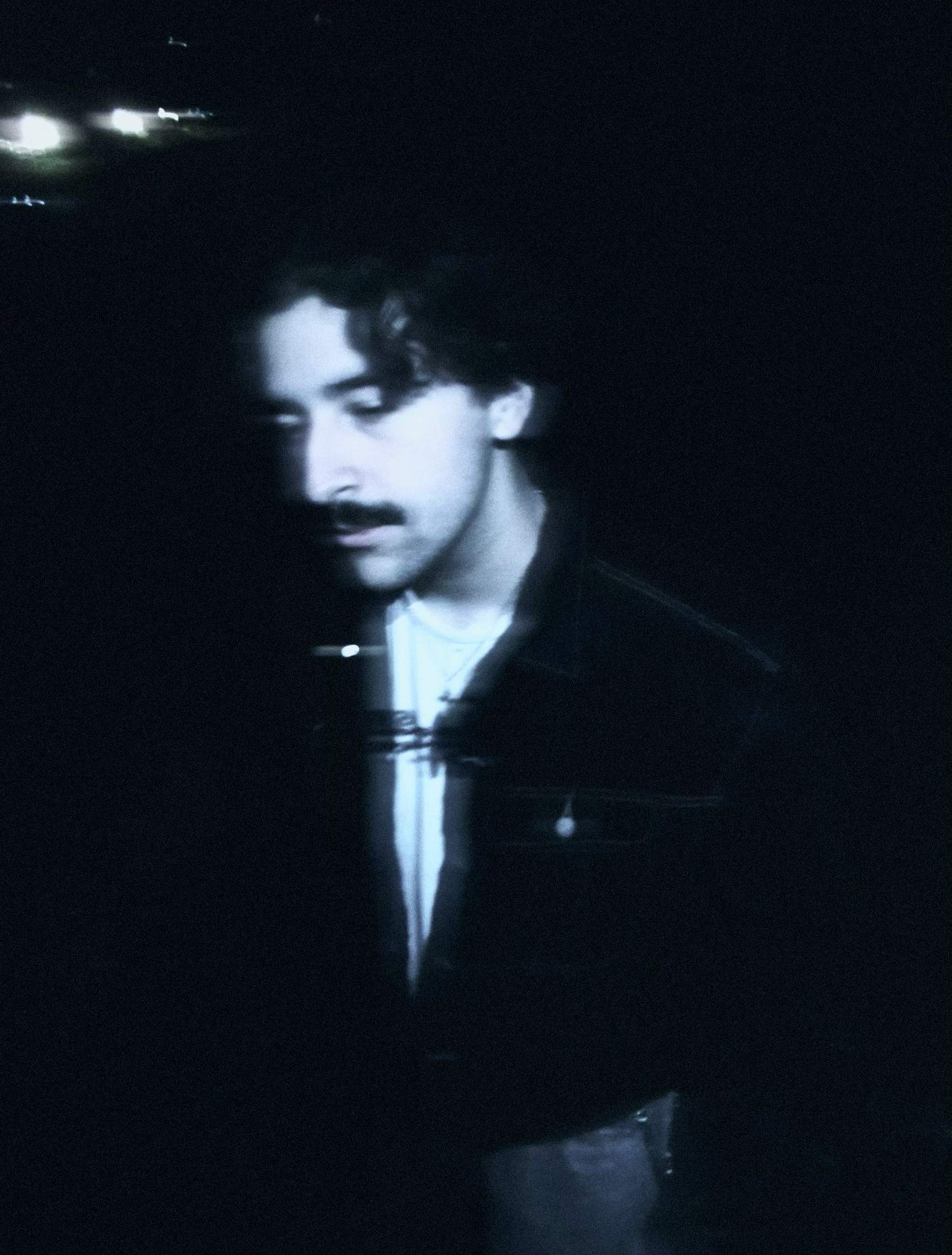 a man with a mustache standing in the dark