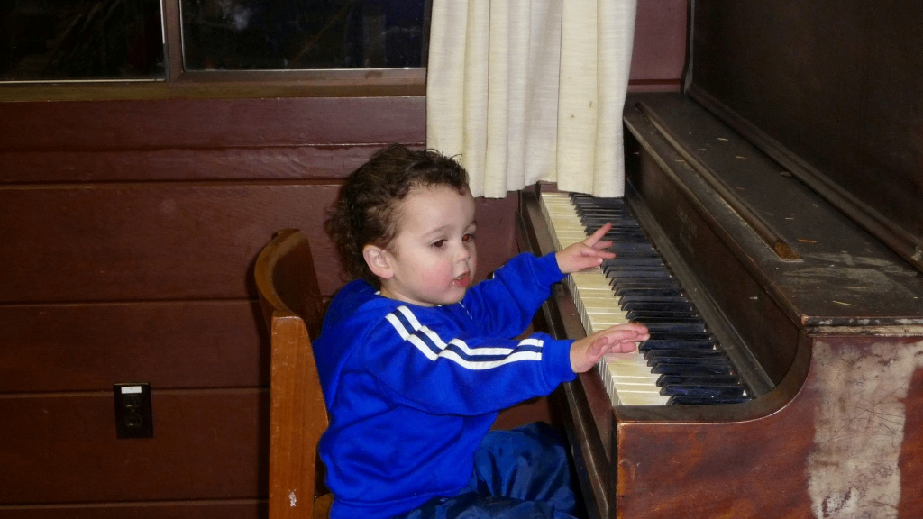 a young boy playing a piano in an old house