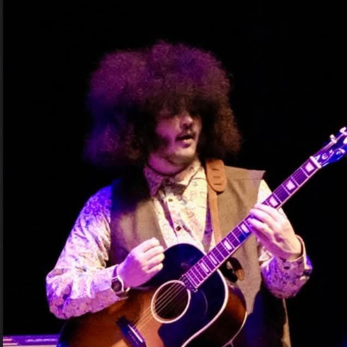 a man with afro hair playing an acoustic guitar