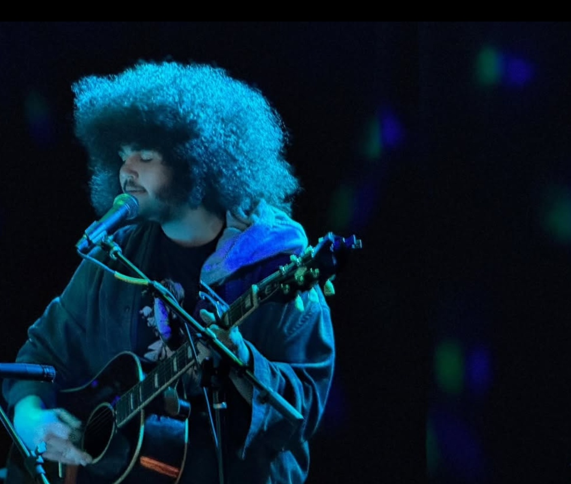 a man with an afro playing an acoustic guitar
