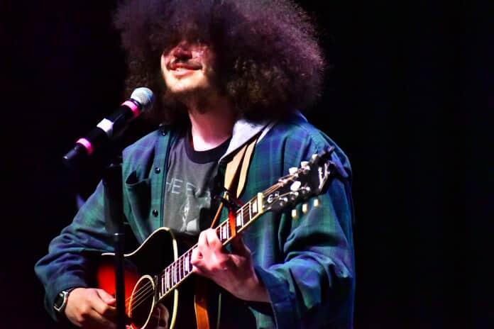 a man with afro hair singing into a microphone