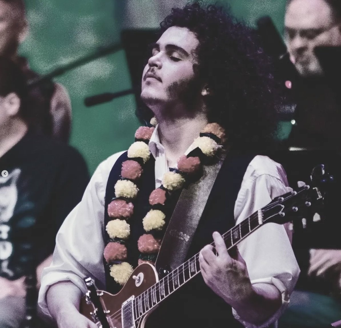 a man with curly hair playing an electric guitar