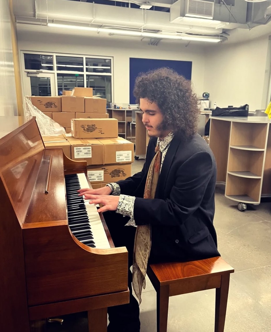 a man playing a piano in a room full of boxes