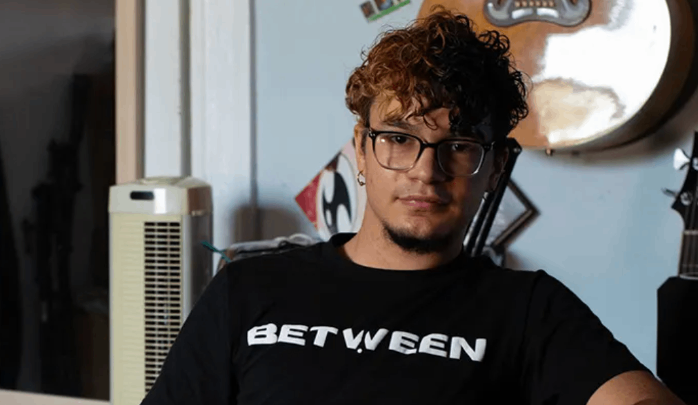 a man with glasses sitting in front of a guitar
