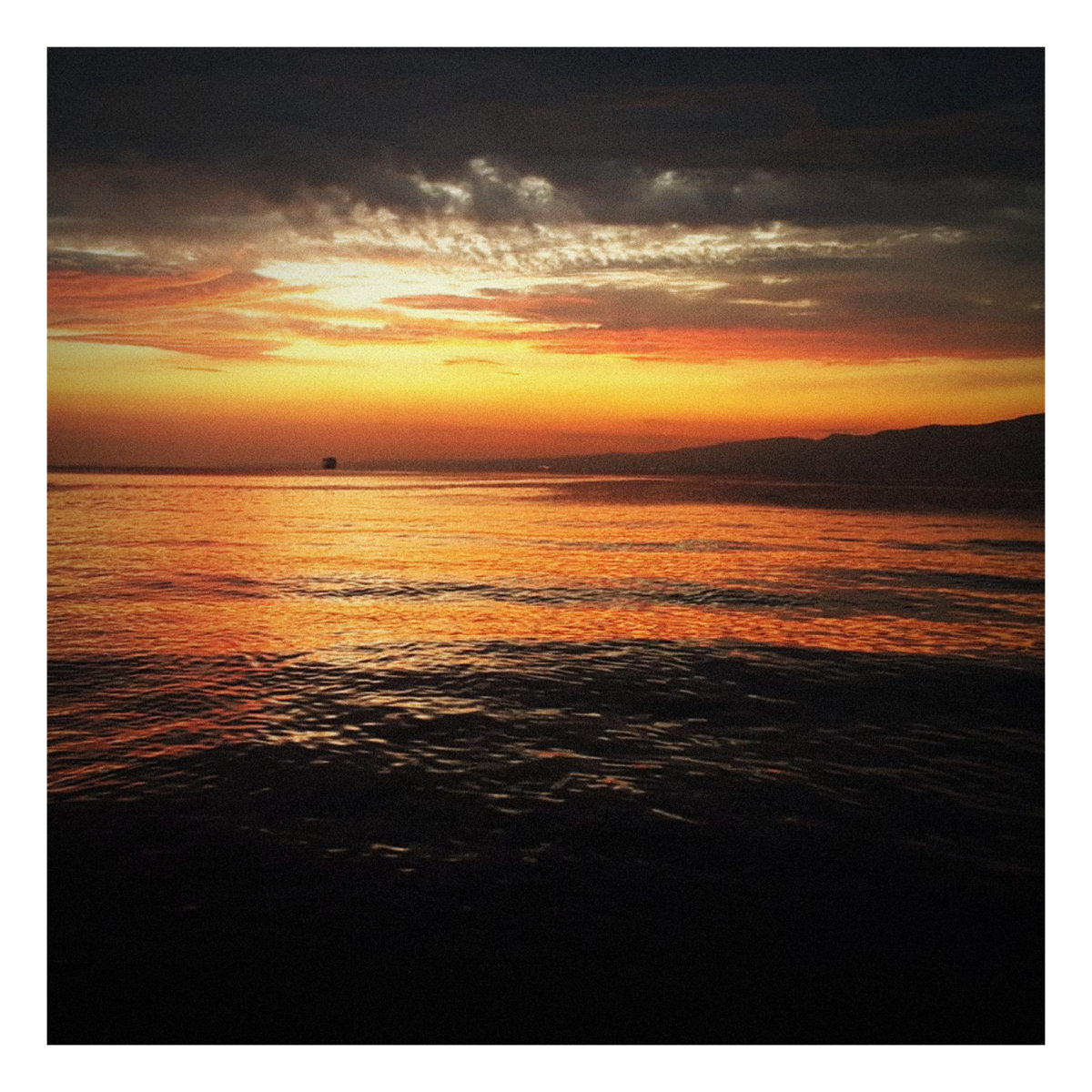 Ozan Aydın - At Dusk: a boat in the water at sunset