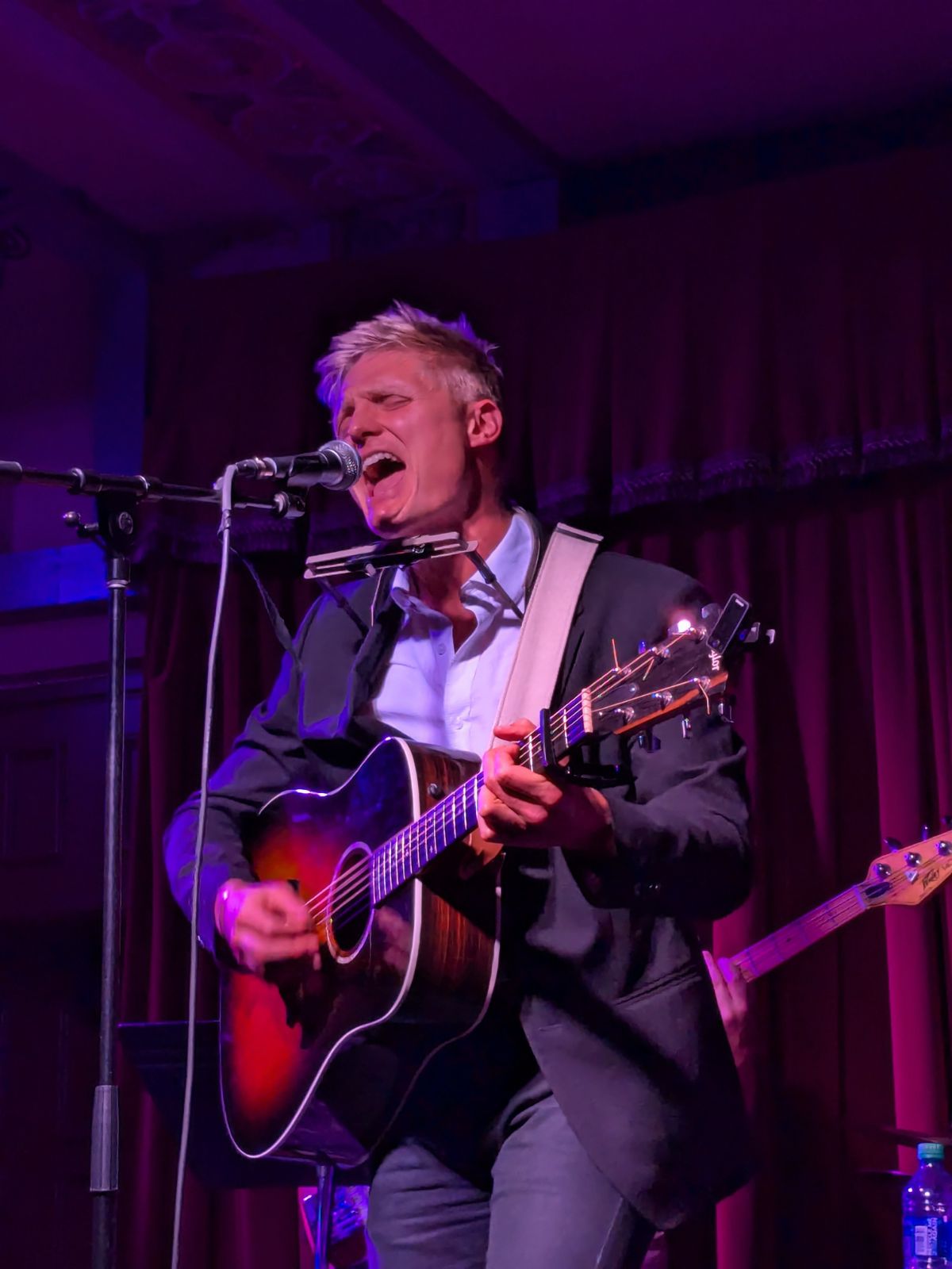 a man singing into a microphone while playing an acoustic guitar