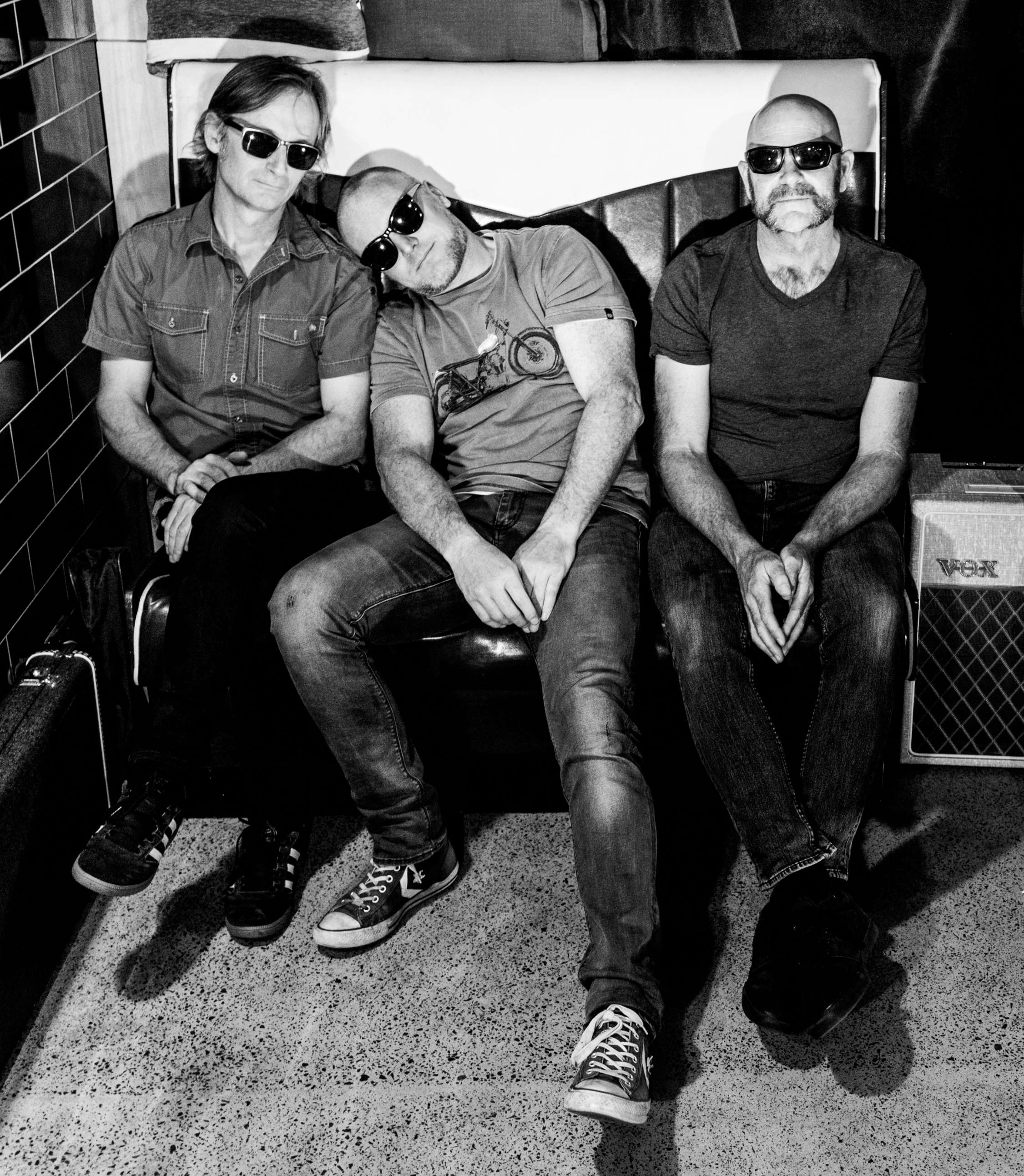 a black and white photo of a group of men sitting on a bench