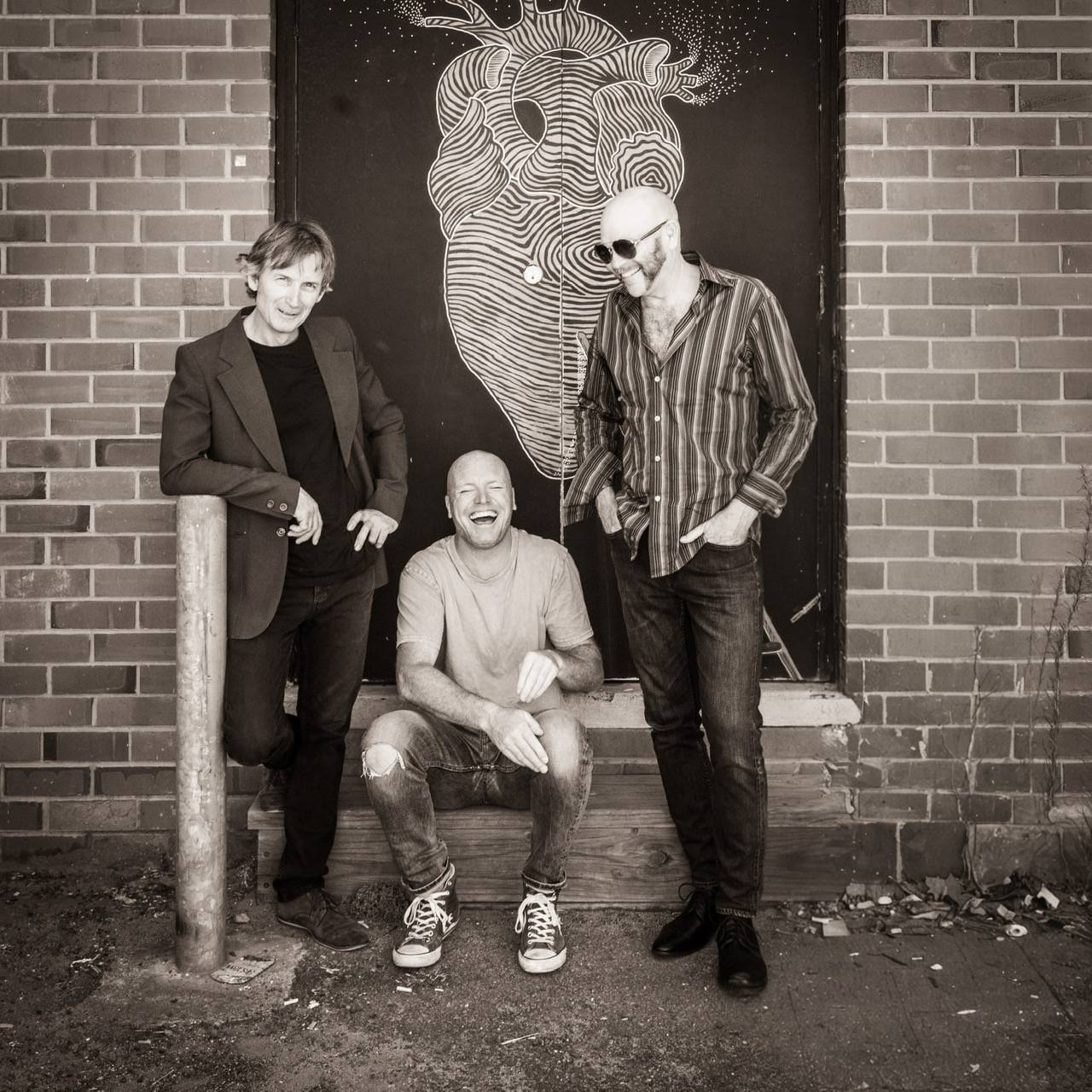 three men posing in front of a brick wall