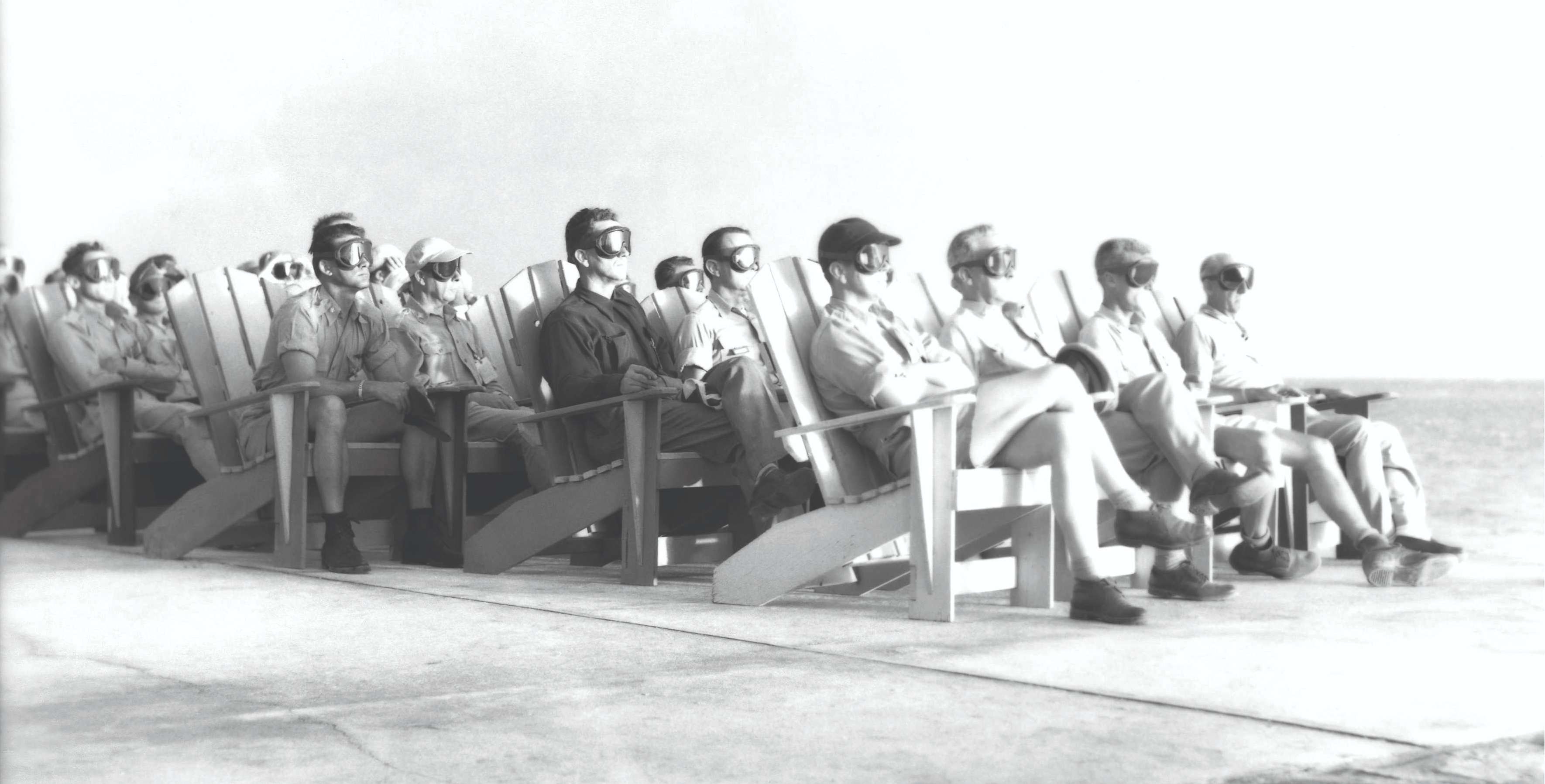a group of men sitting in chairs on the beach