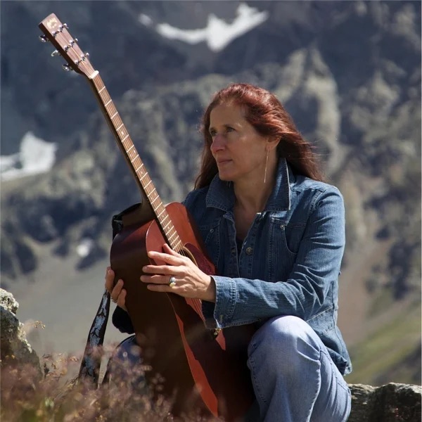 Beth Wimmer - Peace At Christmas: a woman sitting on top of a mountain with an acoustic guitar