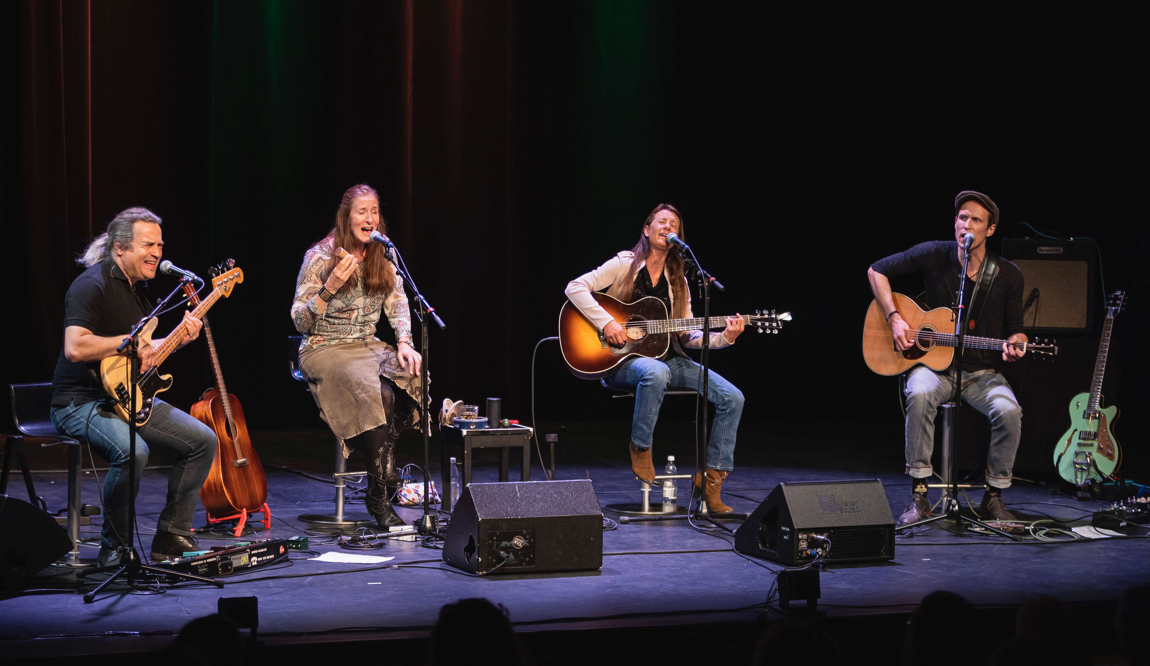 a group of people singing and playing guitars on stage