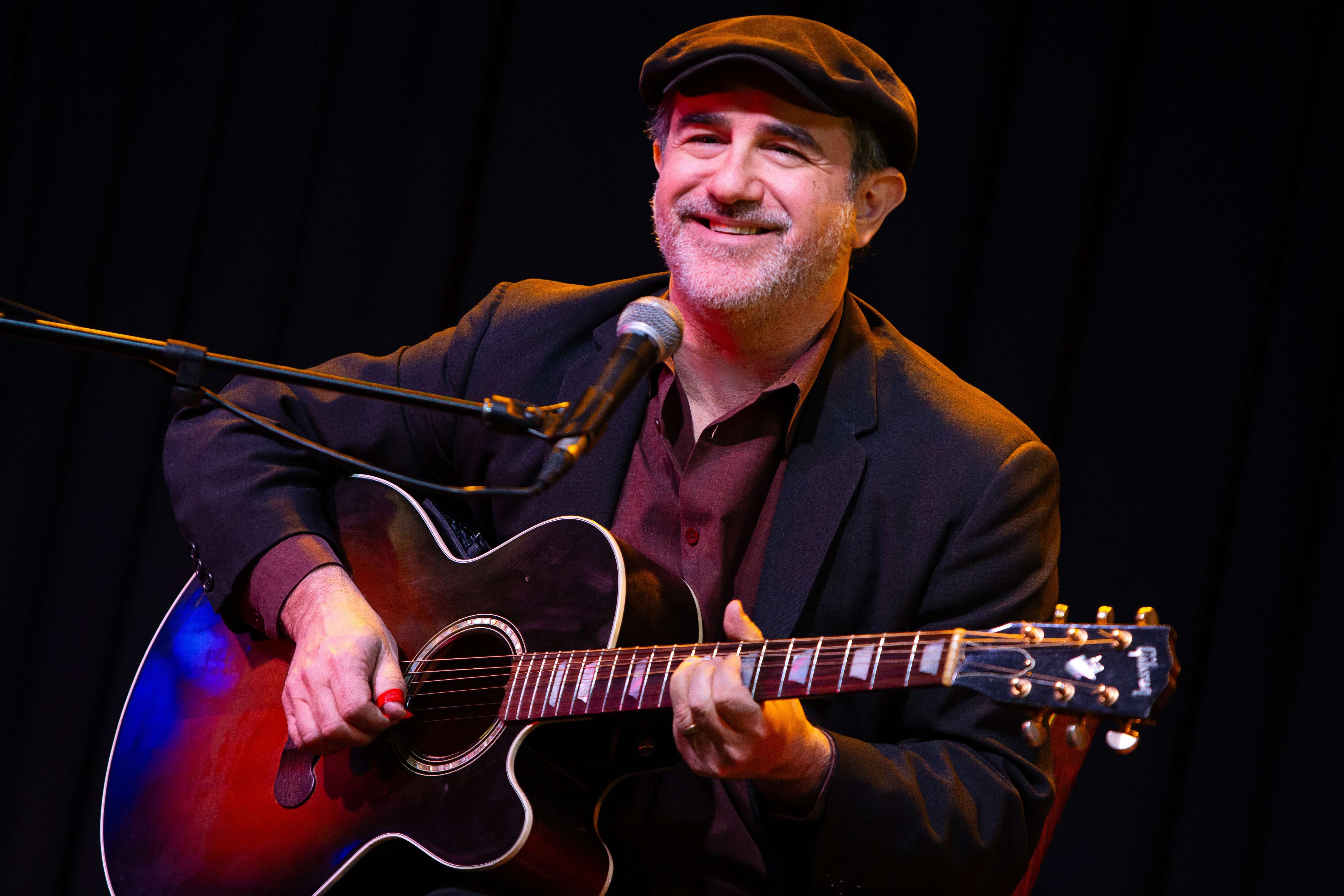 a man playing an acoustic guitar in front of a microphone