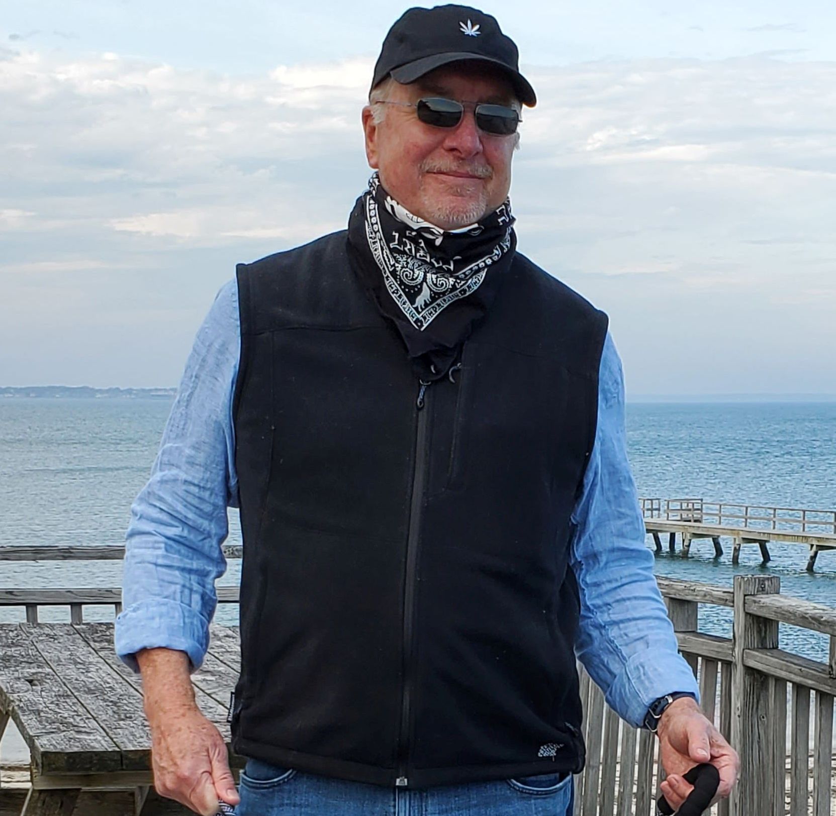 a man in a black vest standing next to the ocean