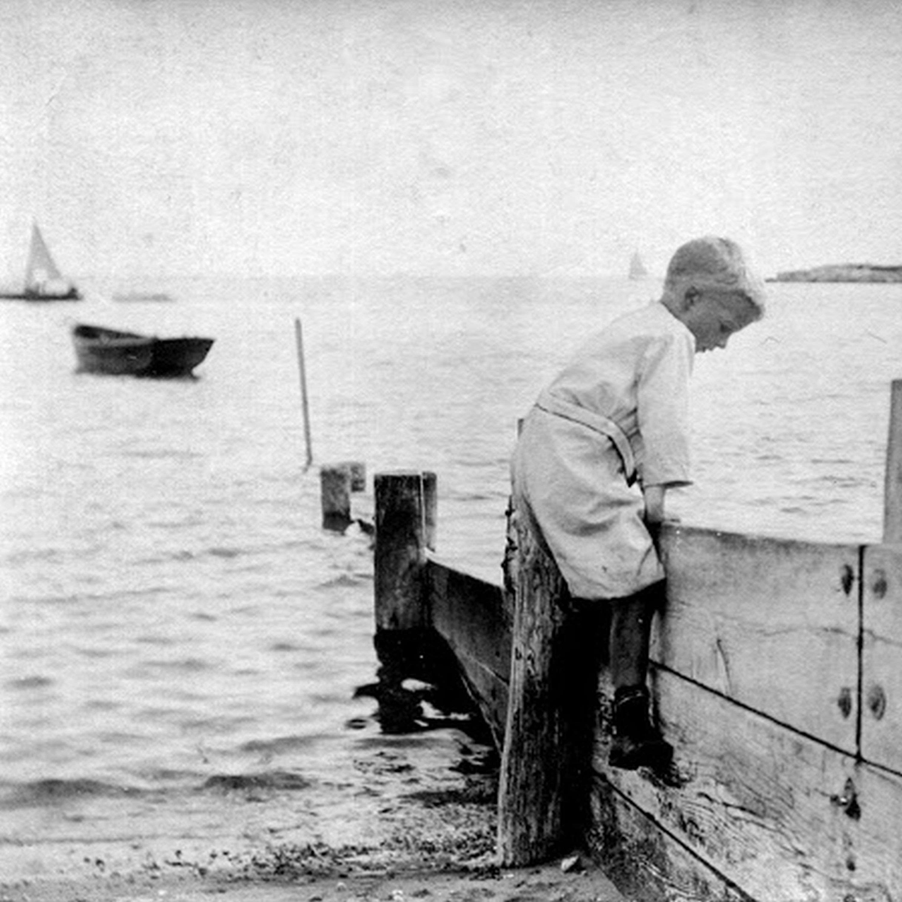 Buzz Goddard - Early Daze: an old photo of a boy leaning over a wooden fence